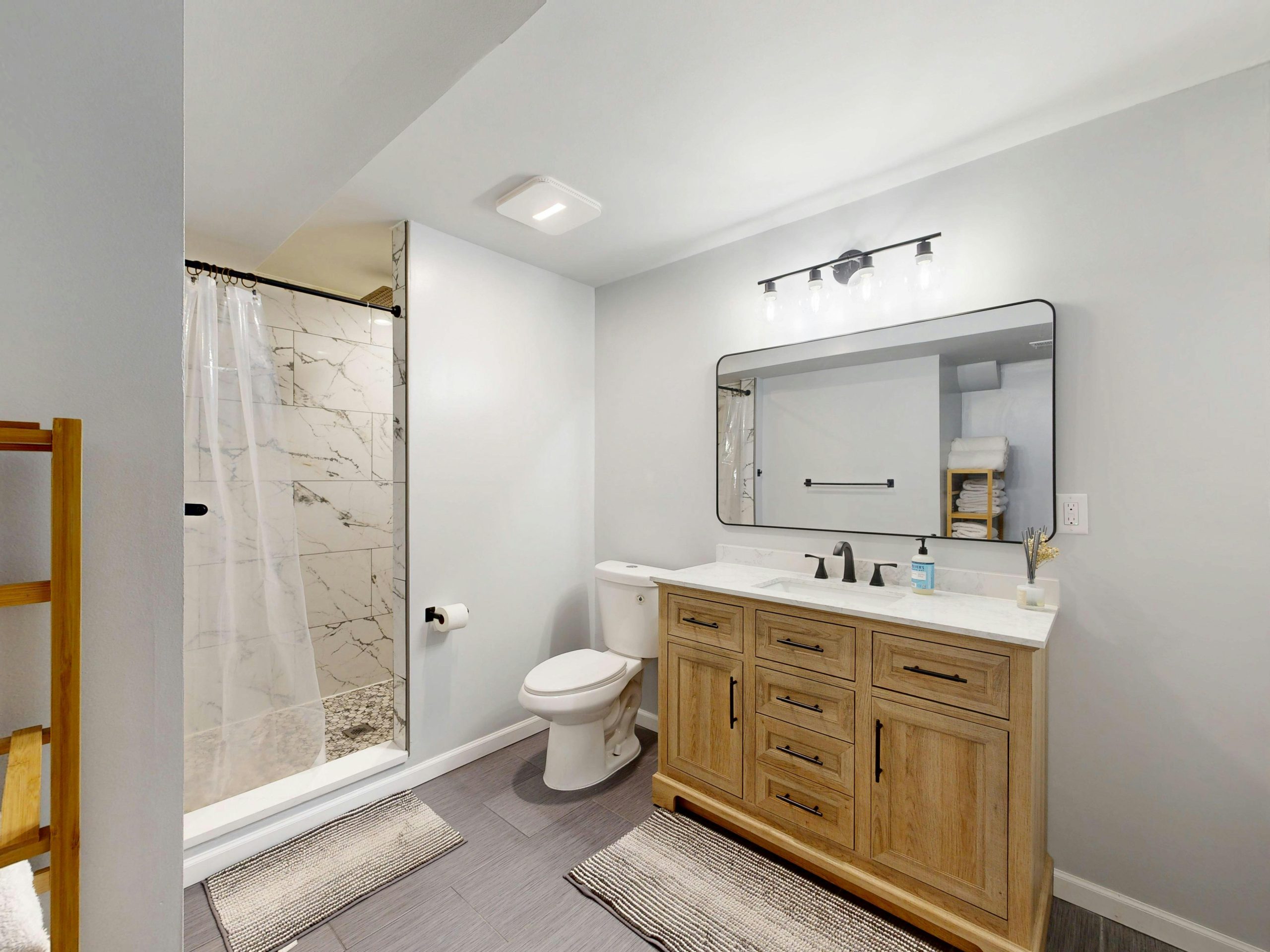 A stylish bathroom featuring a wooden vanity, shower, and sleek fixtures.