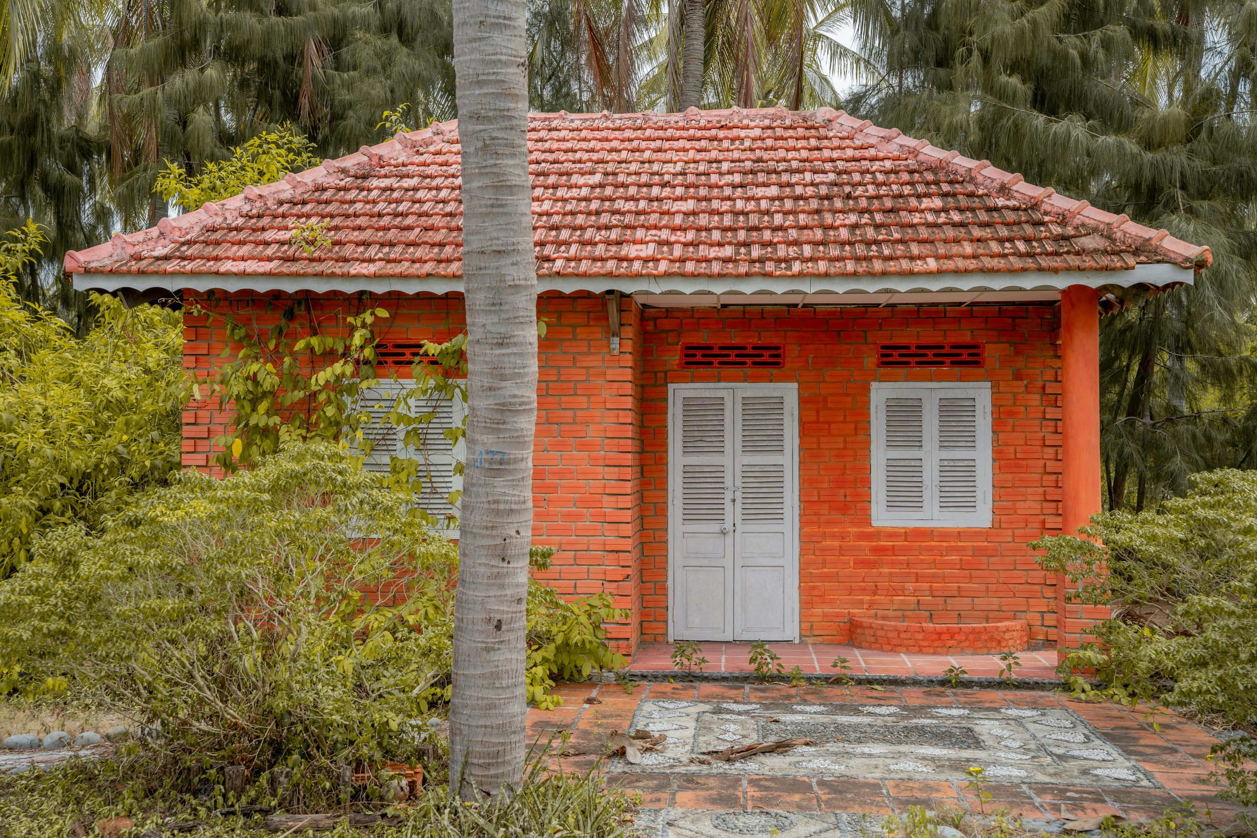 A traditional red brick cottage amidst lush foliage, perfect for rustic retreats.