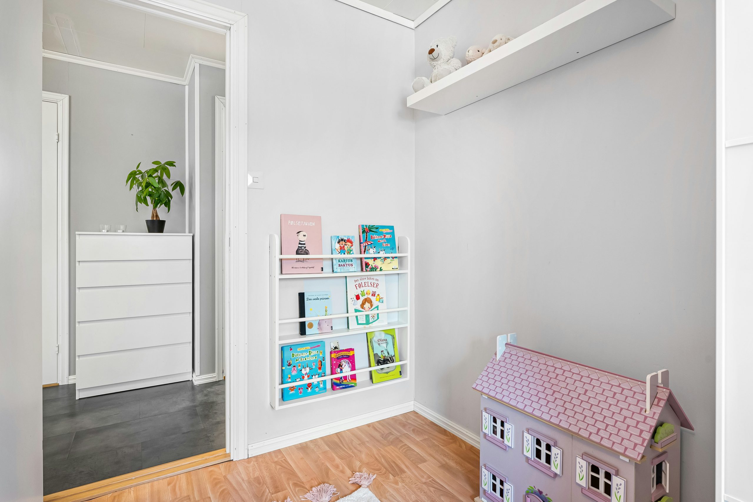A white room with a pink doll house on the floor
