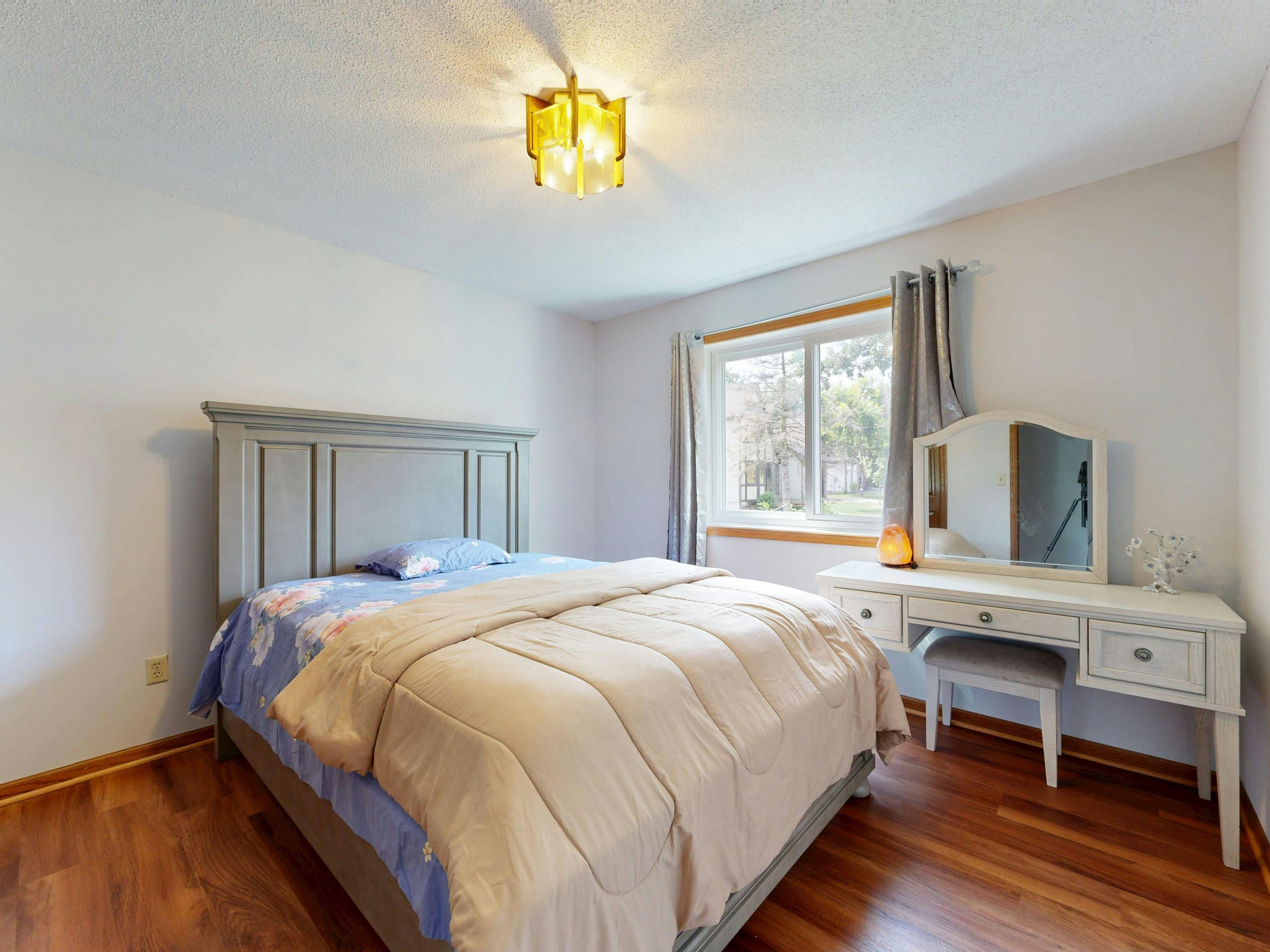 Bright bedroom featuring a comfy bed and wooden furniture with natural light.