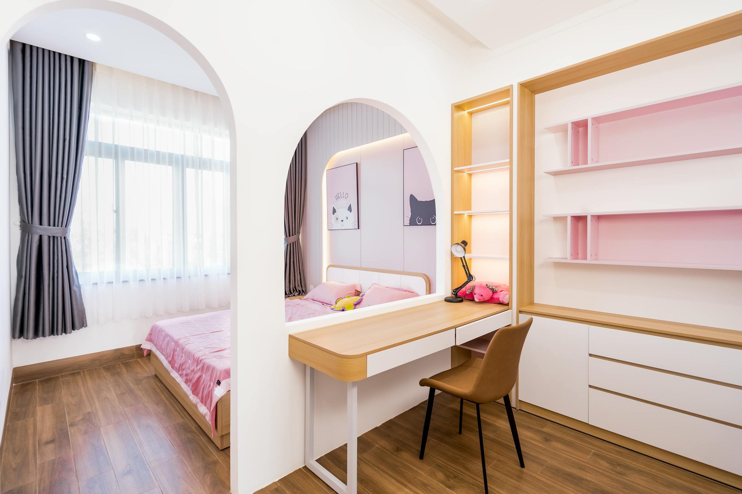 Bright, modern bedroom featuring a stylish pink workspace and cozy bed.