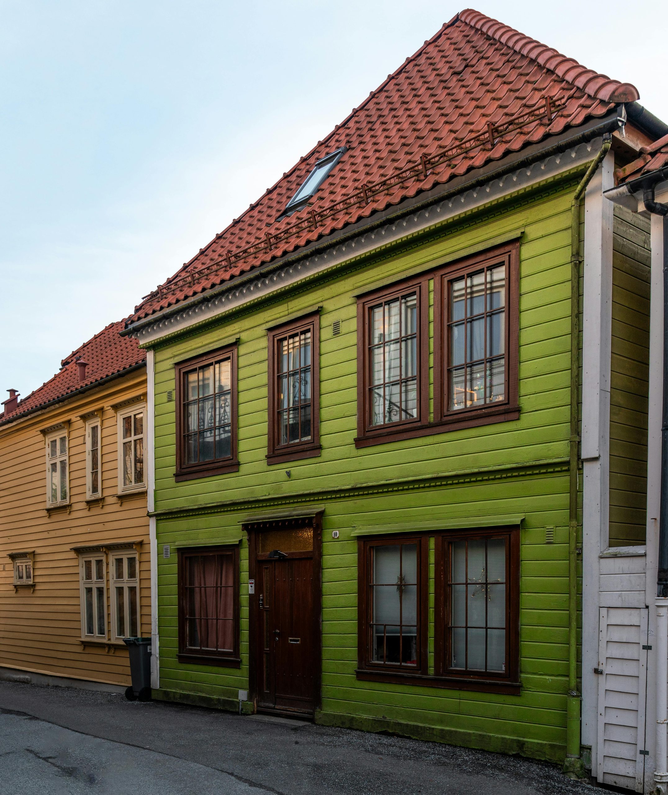 Charming green wooden house with a red tile roof in a picturesque urban setting, perfect for travel and architecture.