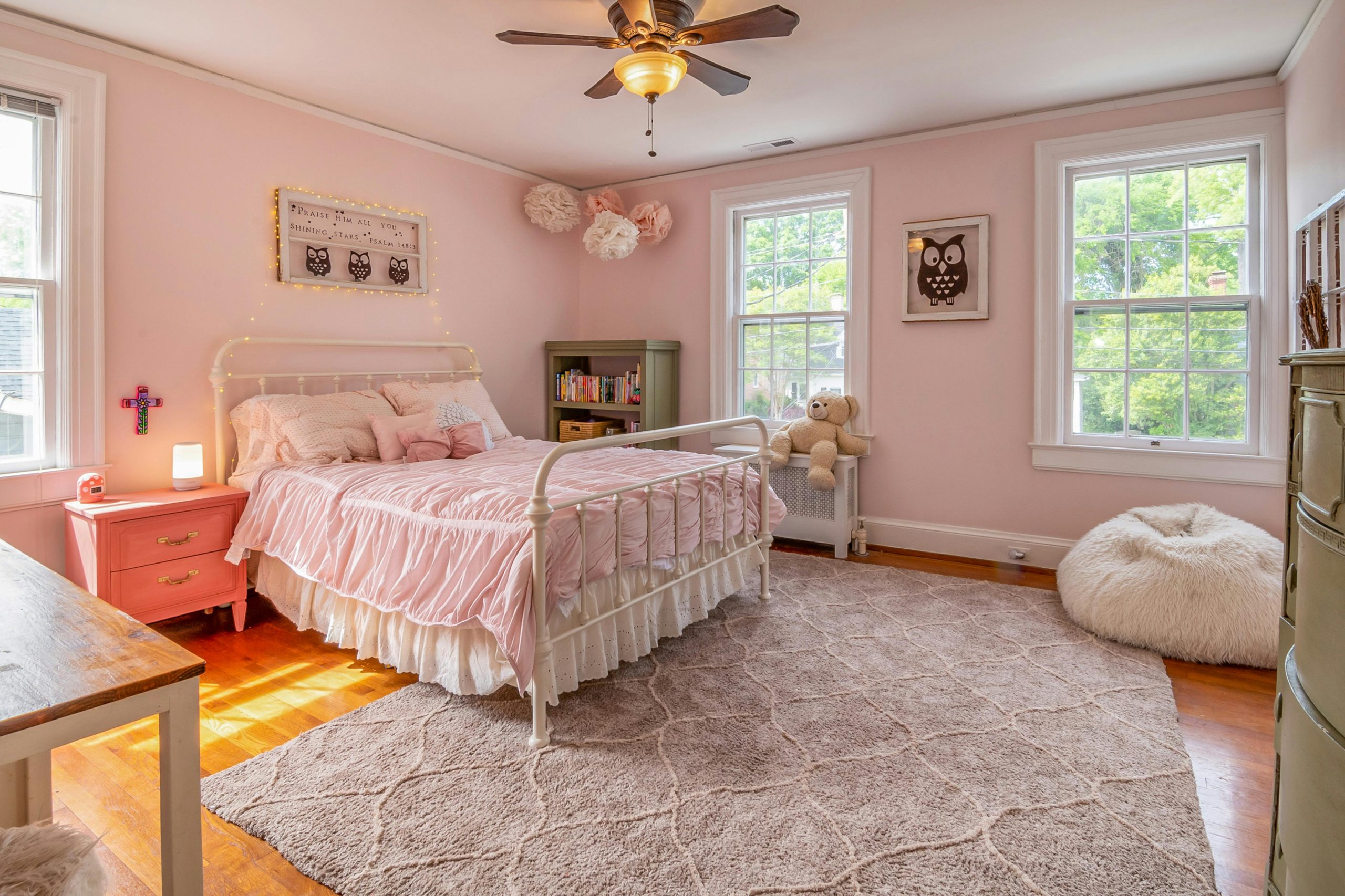 Charming pink bedroom featuring elegant decor, soft lighting, and cozy furnishings.
