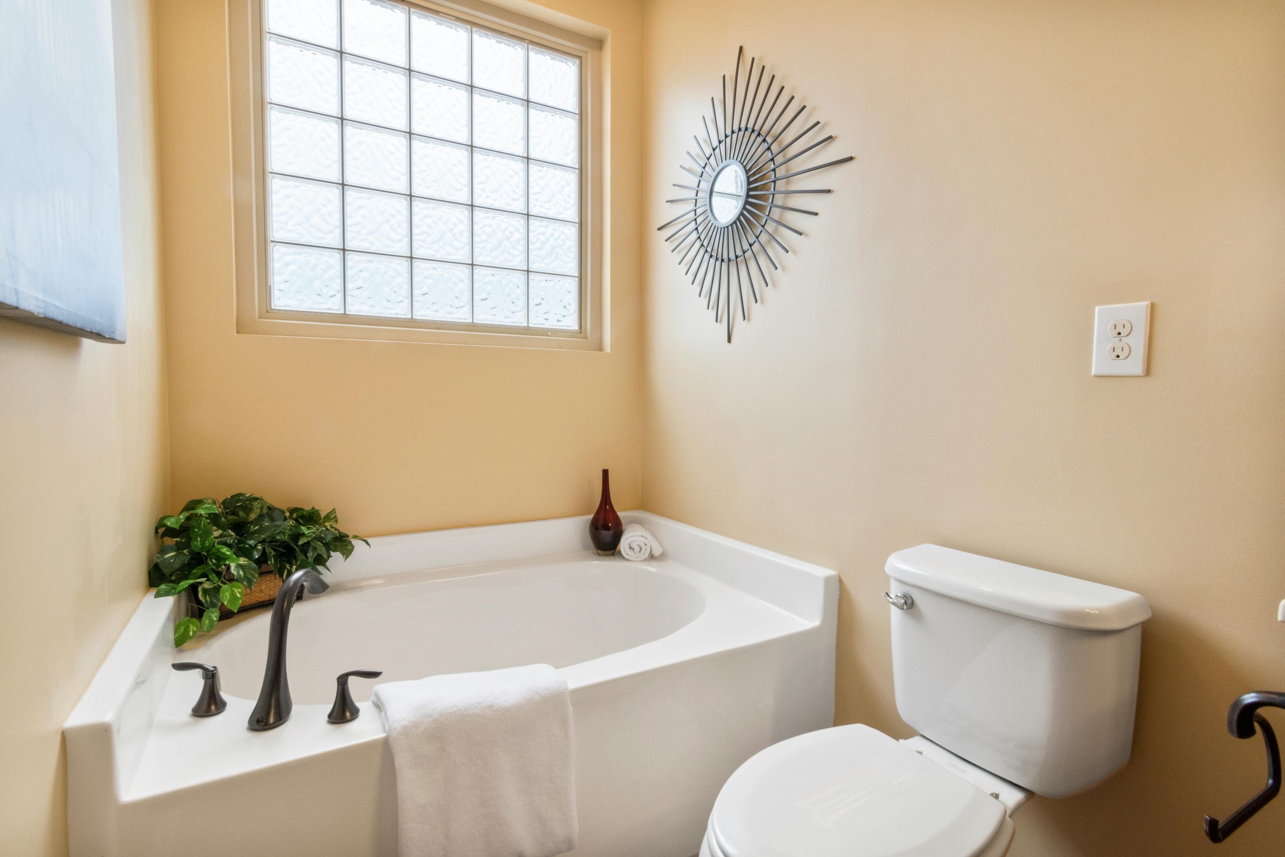 Contemporary bathroom featuring a corner bathtub, toilet, and stylish decor.