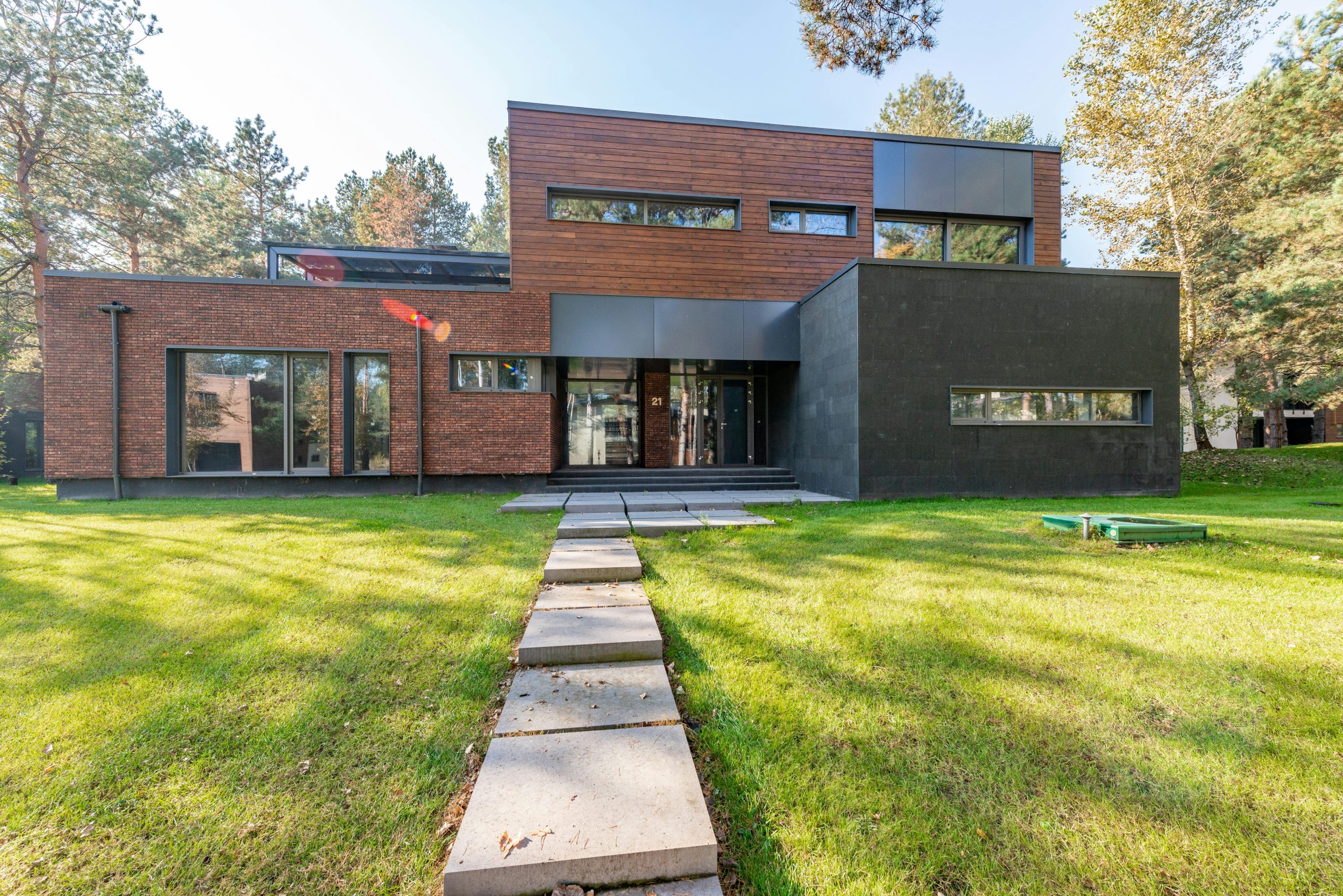 Contemporary building with brick and glass facade, set amidst green lawn.