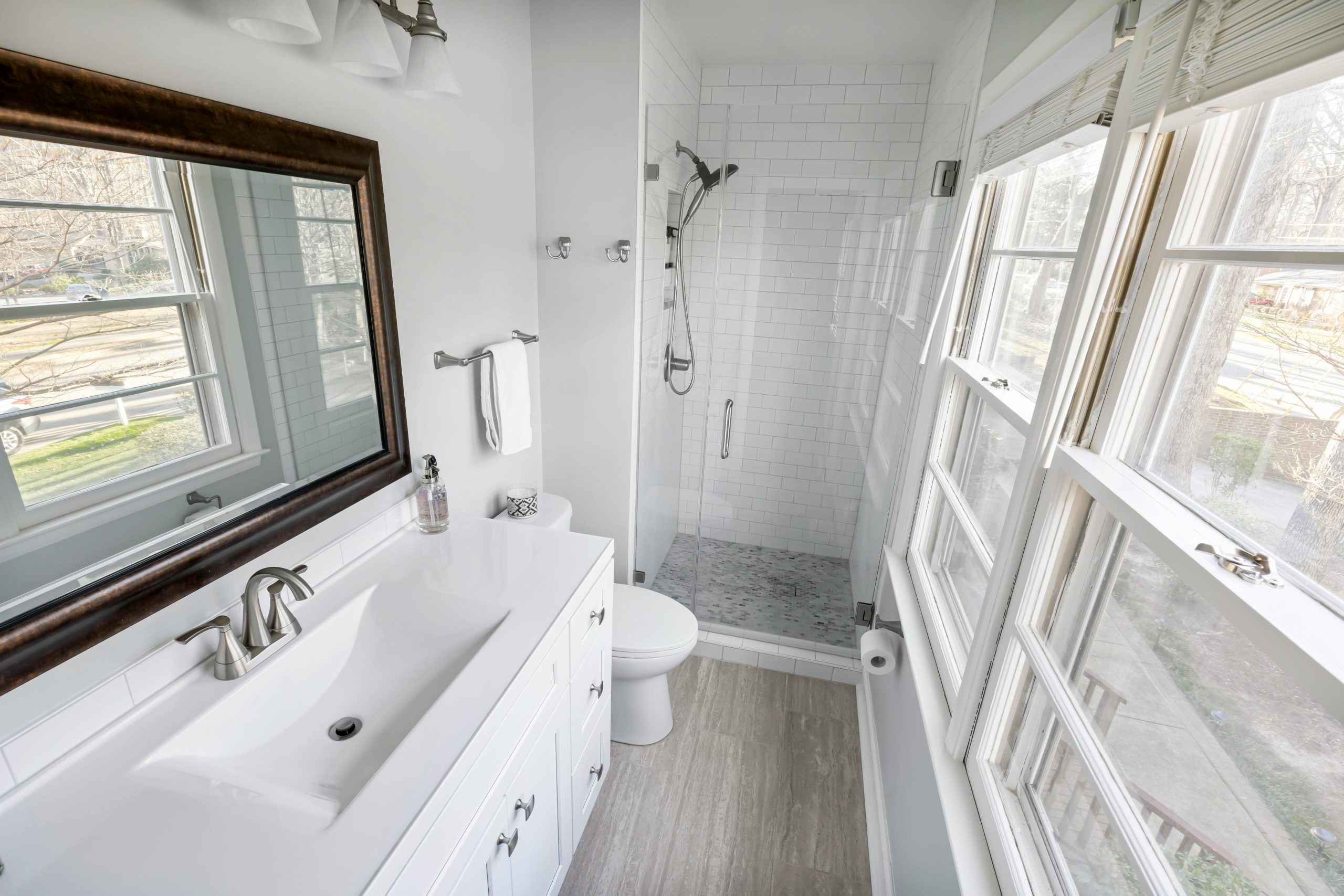 Contemporary minimalist bathroom featuring a tiled shower, vanity, and ample natural light.
