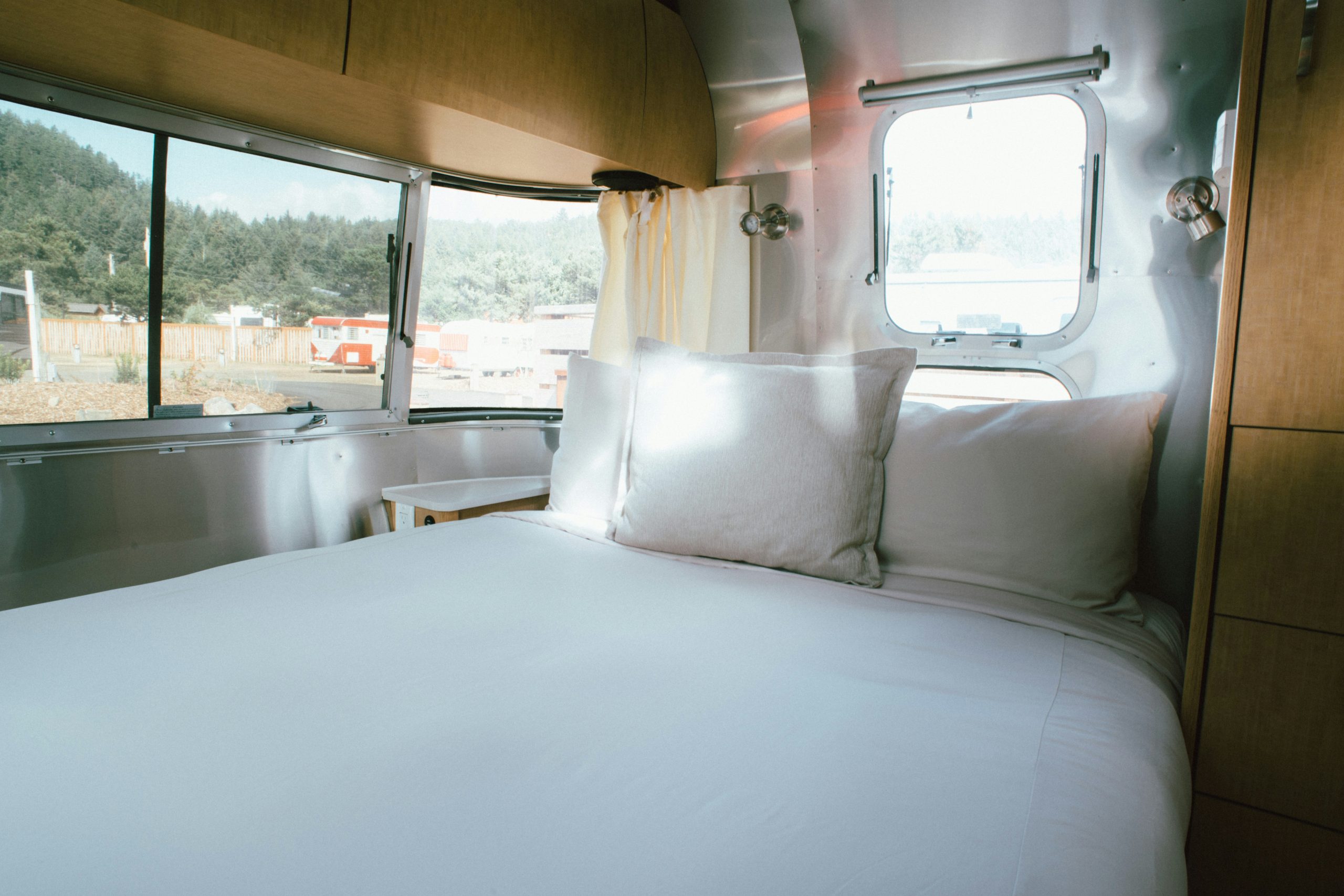 Cozy camper van interior featuring a comfortable bed with white linens, showcasing van life and mobile travel lifestyle in a compact space.