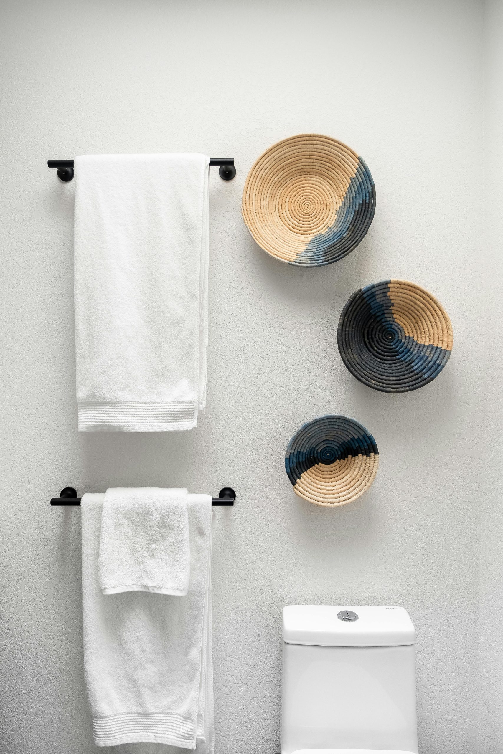 Elegant bathroom featuring woven art and towels in a minimalist style.