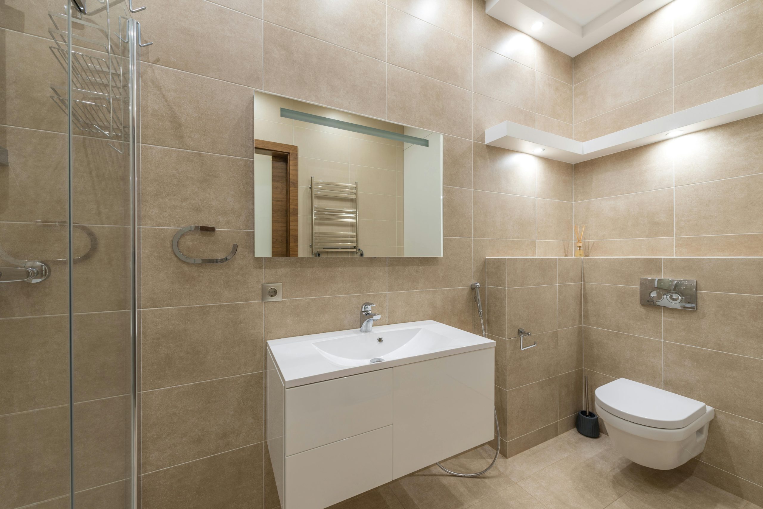 Elegant bathroom with modern fixtures and beige tiles.