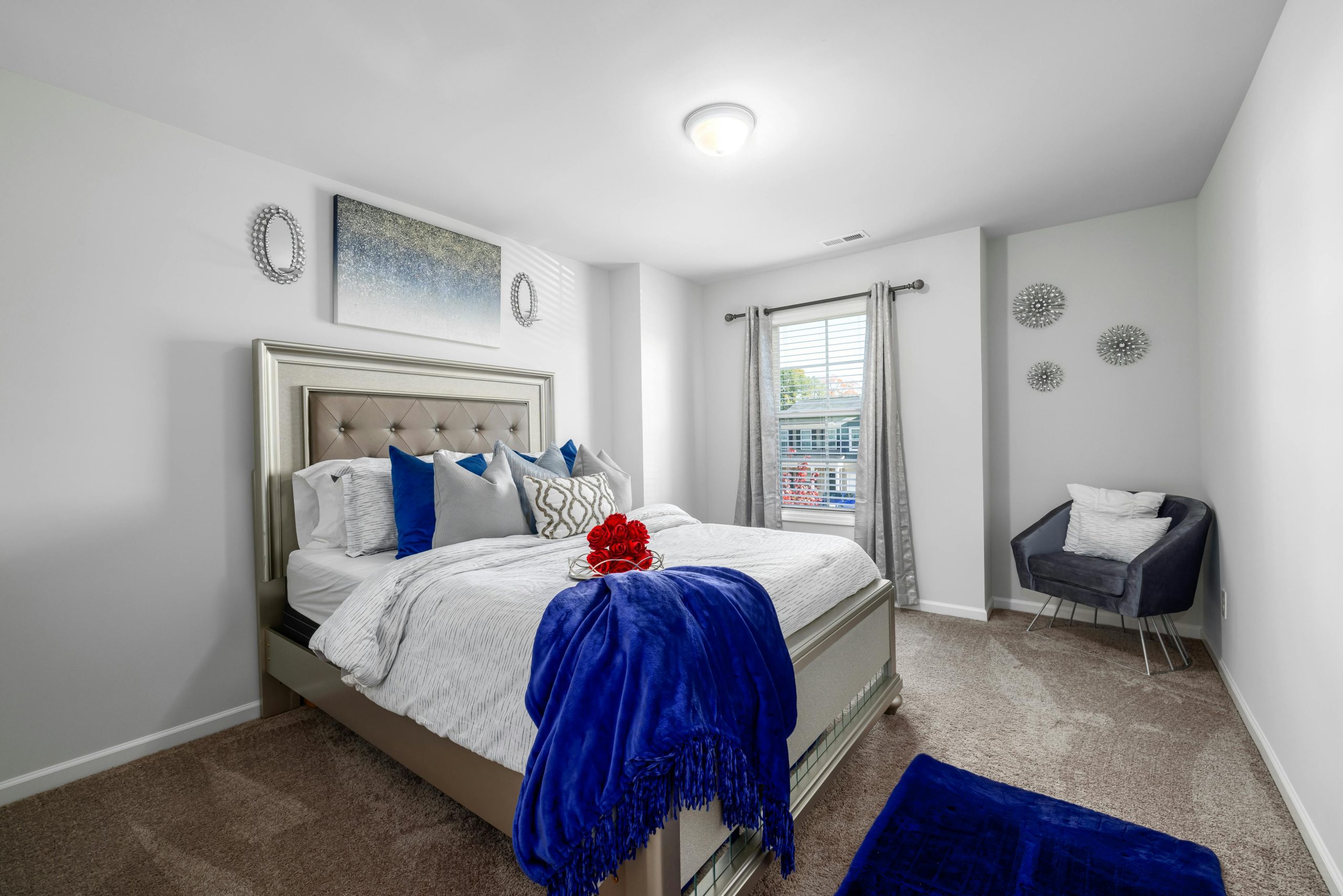 Elegant bedroom interior featuring a plush bed and armchair with vibrant blue accents.