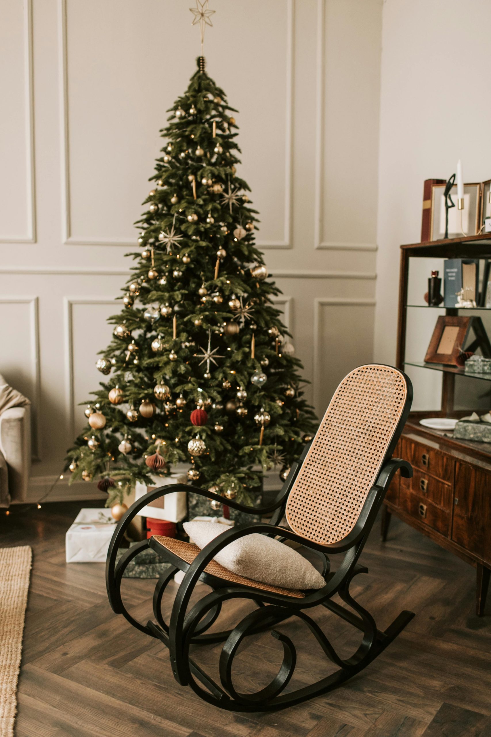 Elegant interior with a decorated Christmas tree and vintage rocking chair, perfect for a festive atmosphere.