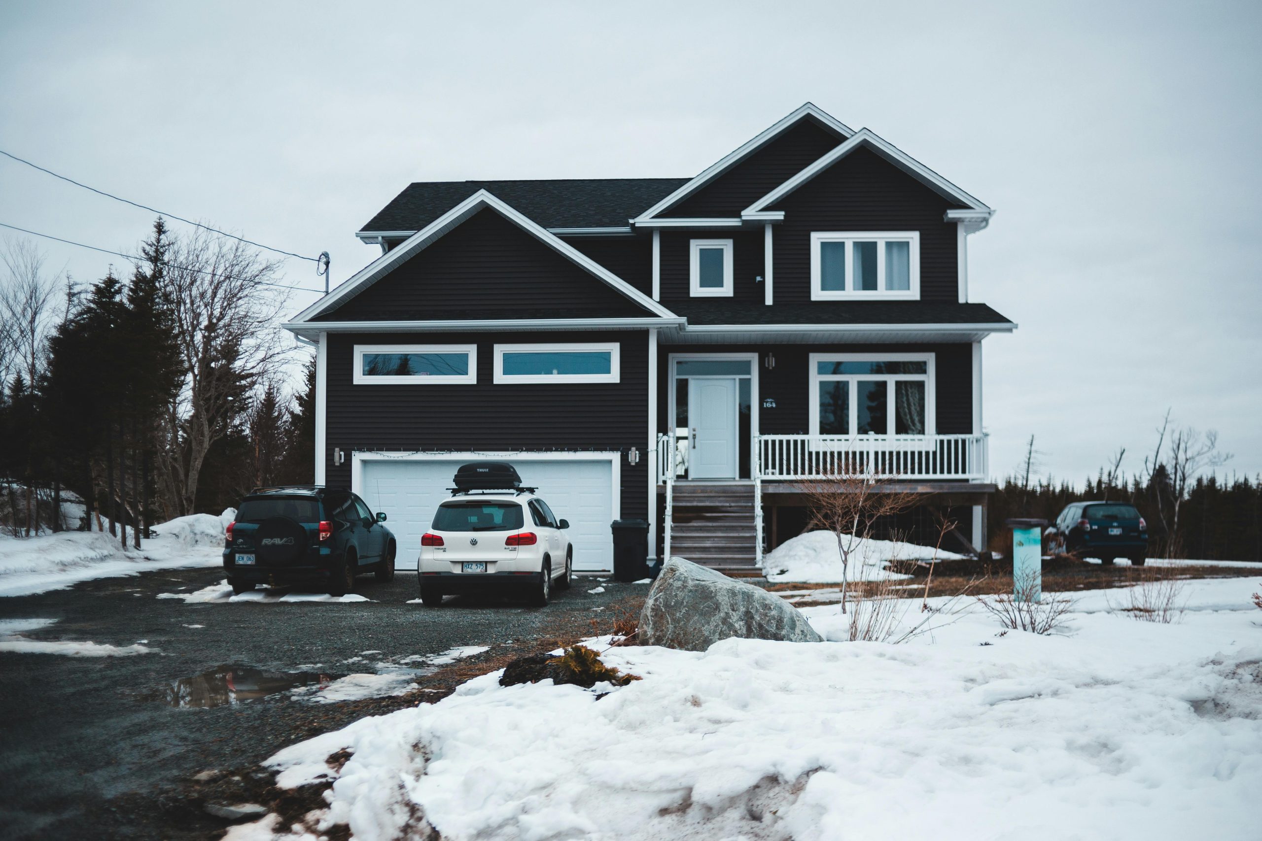 Facade of cottage with cars at garage in countryside covered with snow in winter season