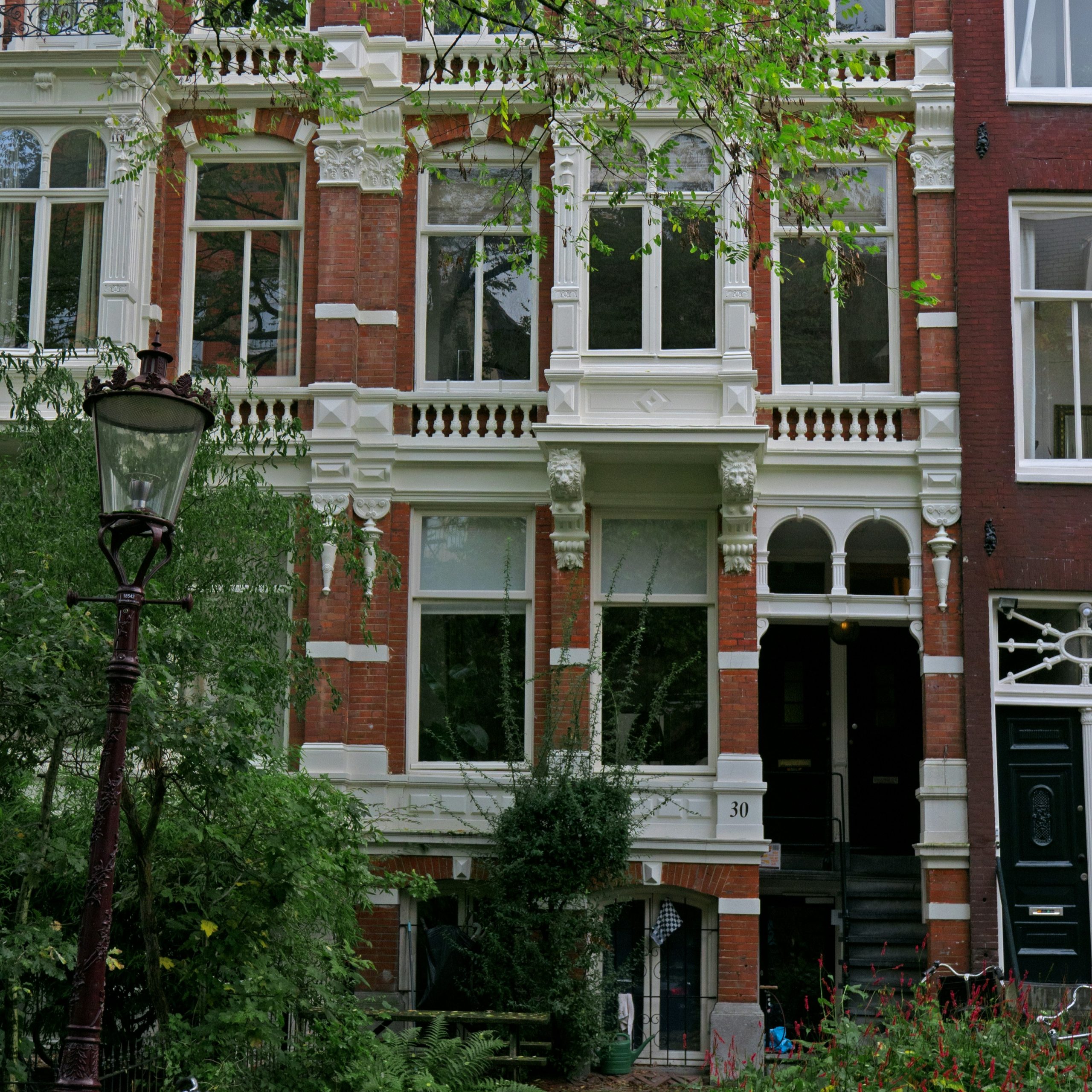 Free photo of brick house facades of residential buildings with window reflections & facade decorations built c. 1880 in Amsterdam city in the Plantagebuurt neighborhood. I like the reflections in the