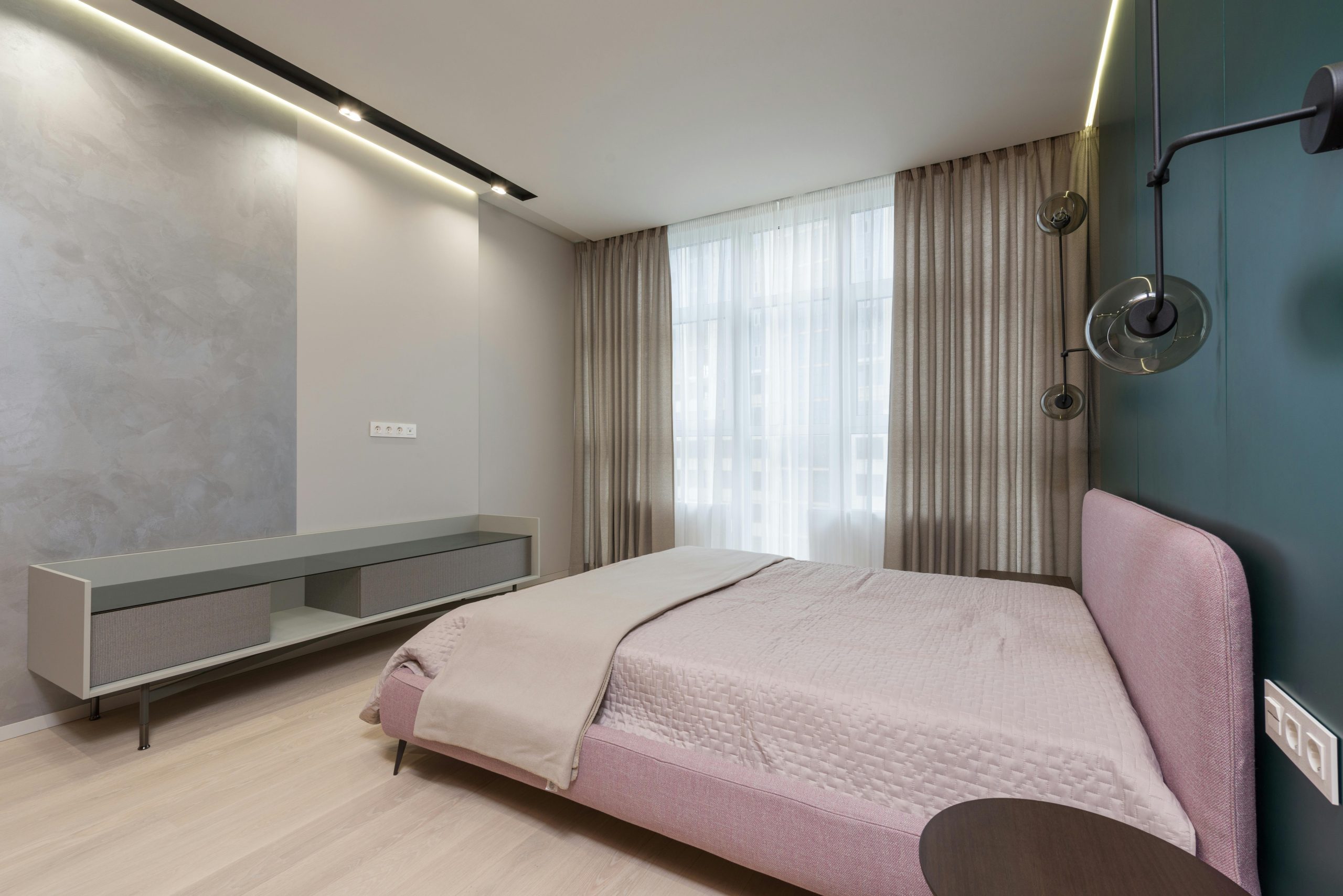Interior of bedroom with minimalist wooden furniture and comfortable bed placed near wall with creative lamps