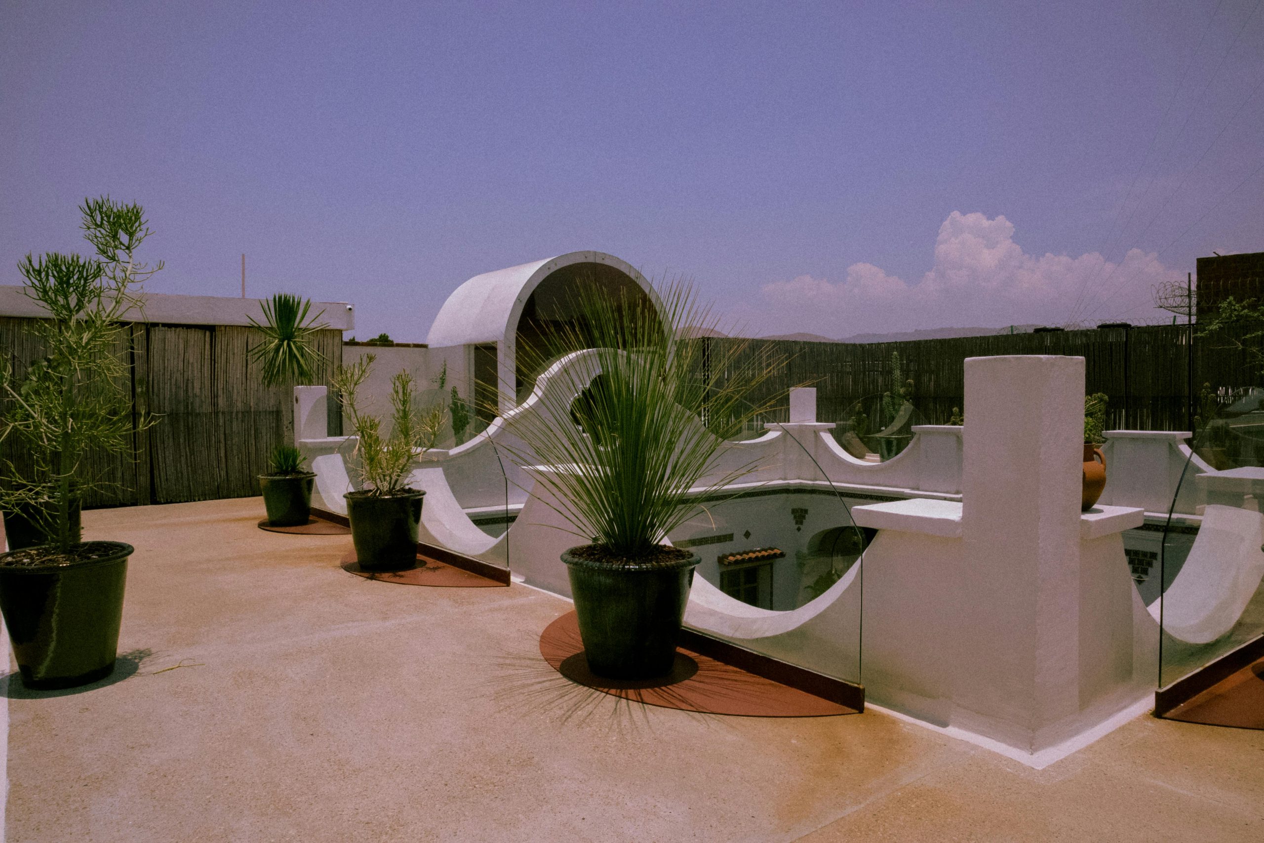 Luxurious urban patio with potted plants and unique architecture under a clear blue sky.