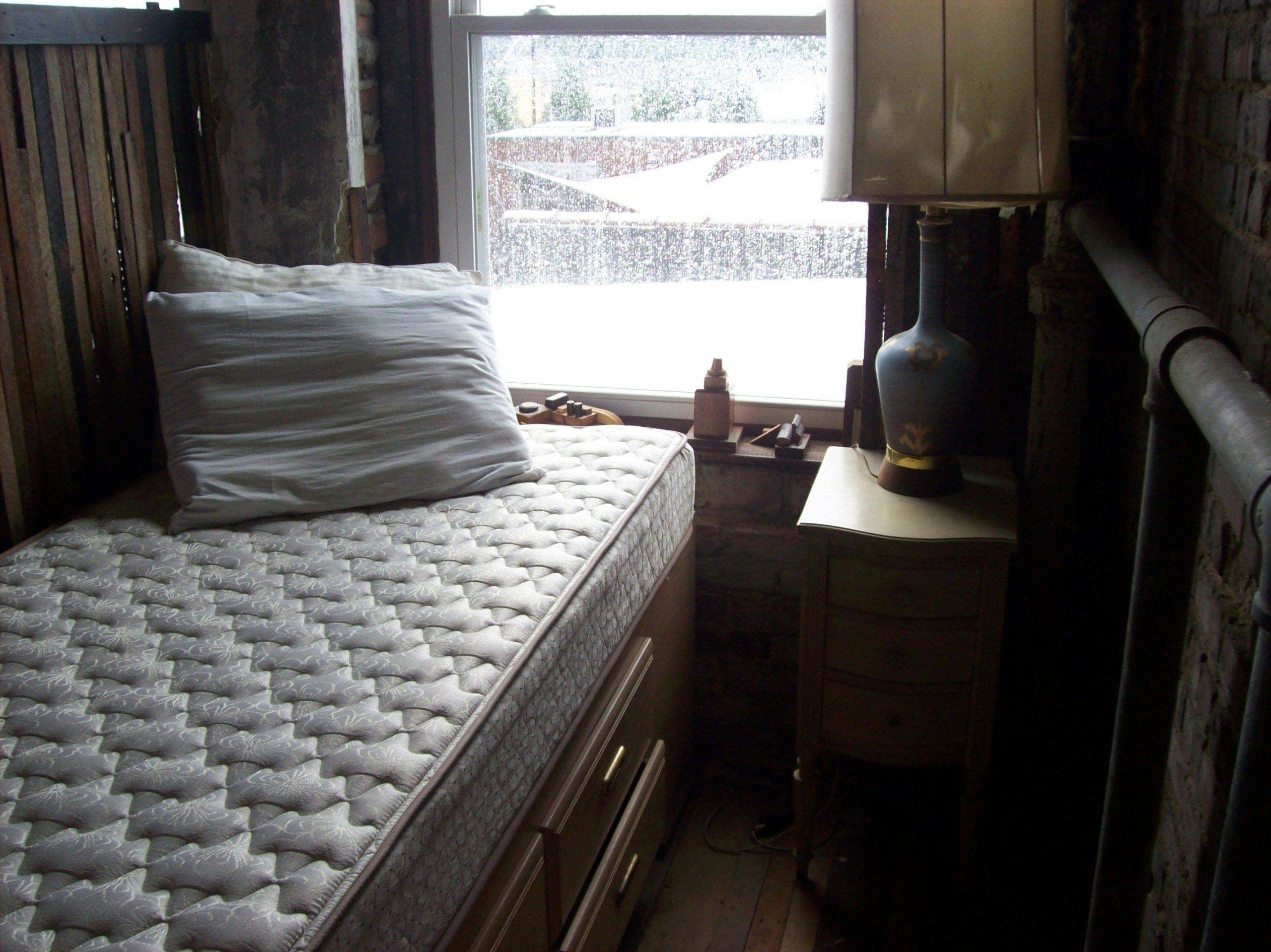 mattress and night stand in front of window