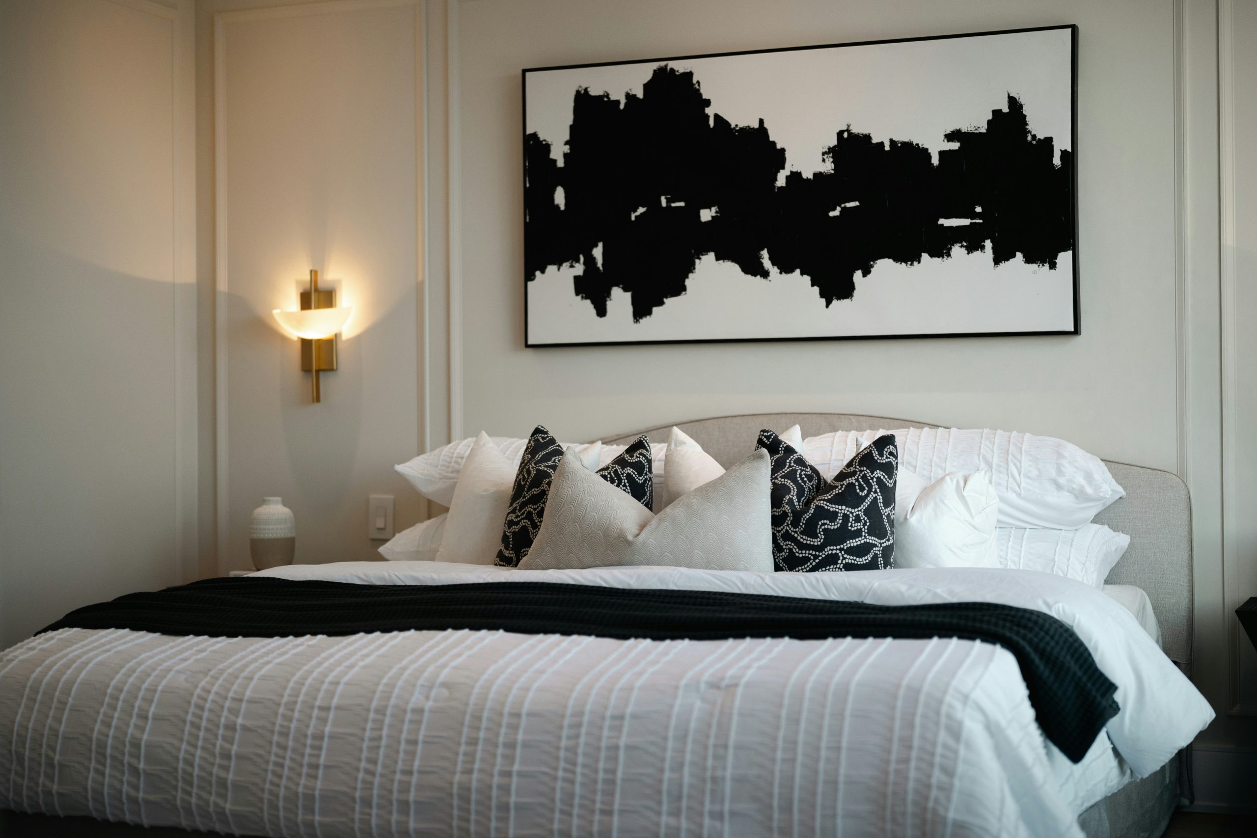 Modern bedroom with abstract art above bed.