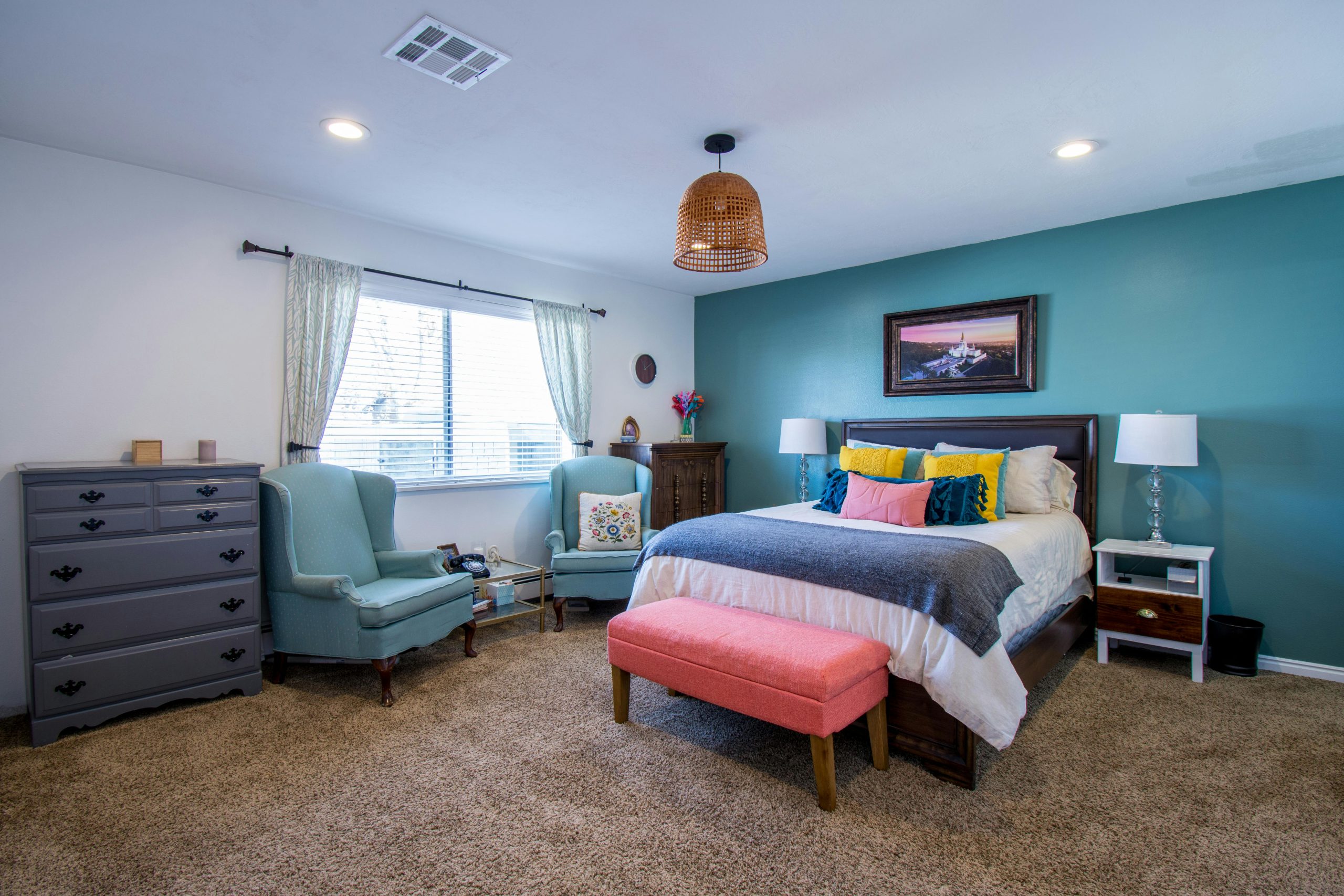 Modern bedroom with vibrant decor, featuring teal walls and comfortable furnishings.
