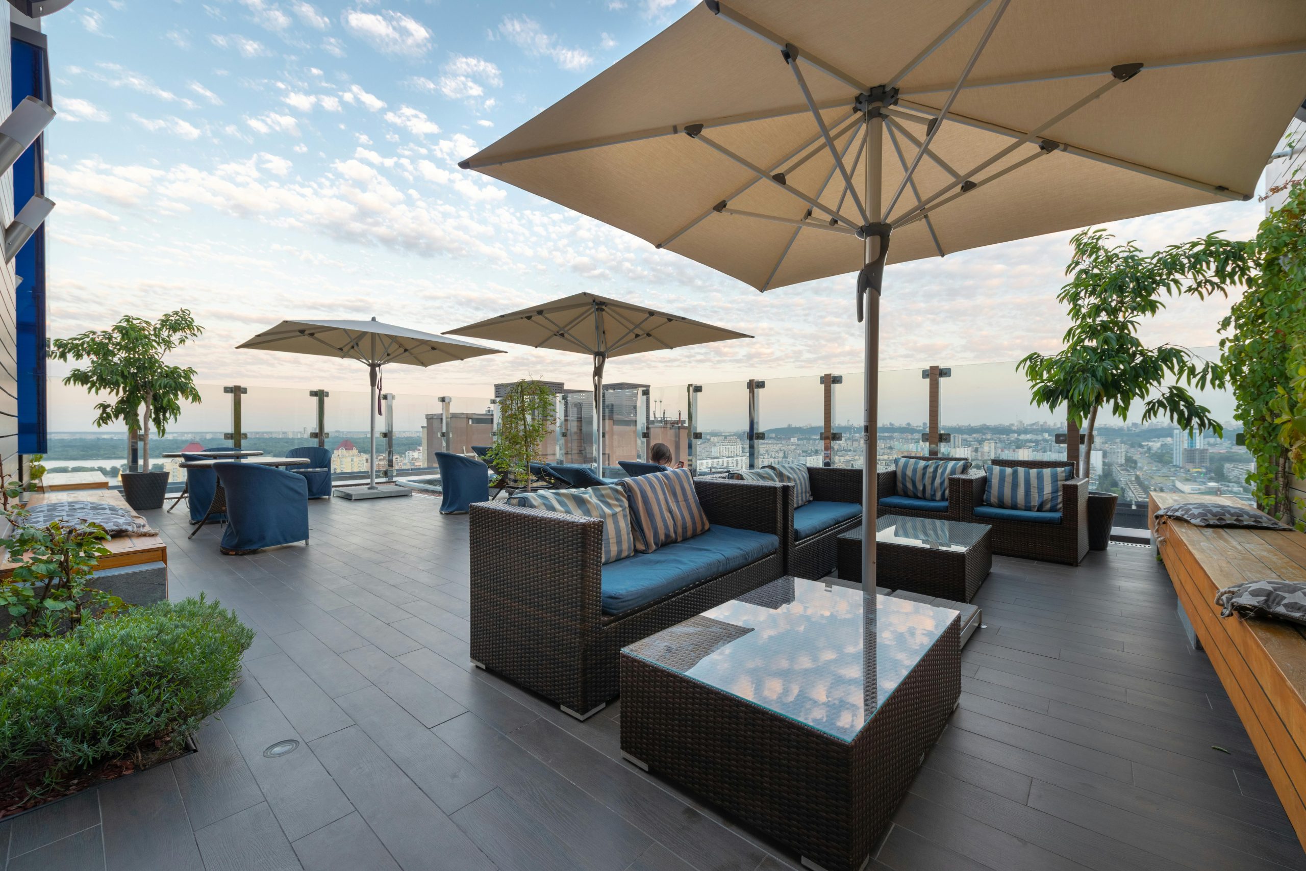 Modern lounge zone with comfortable sofas and tables under umbrellas on terrace in daytime