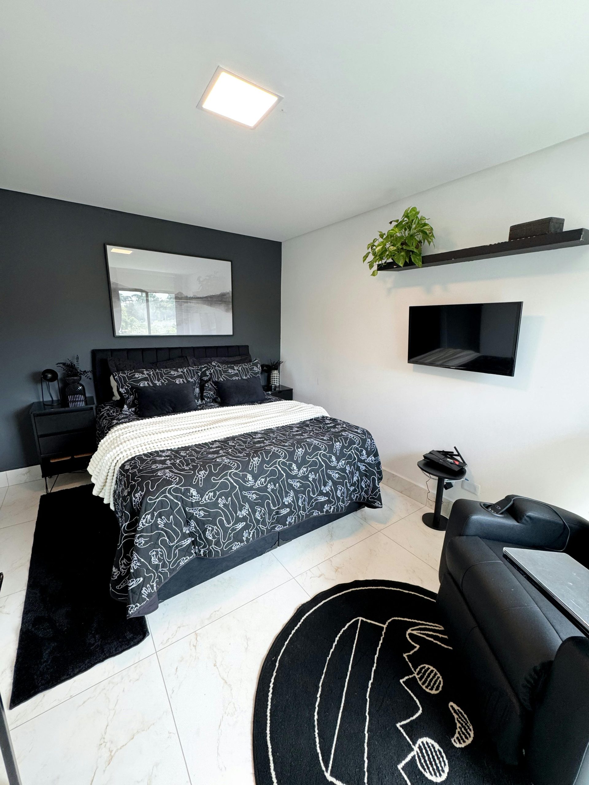 Modern minimalist bedroom with black and white decor, plants, and cozy atmosphere.