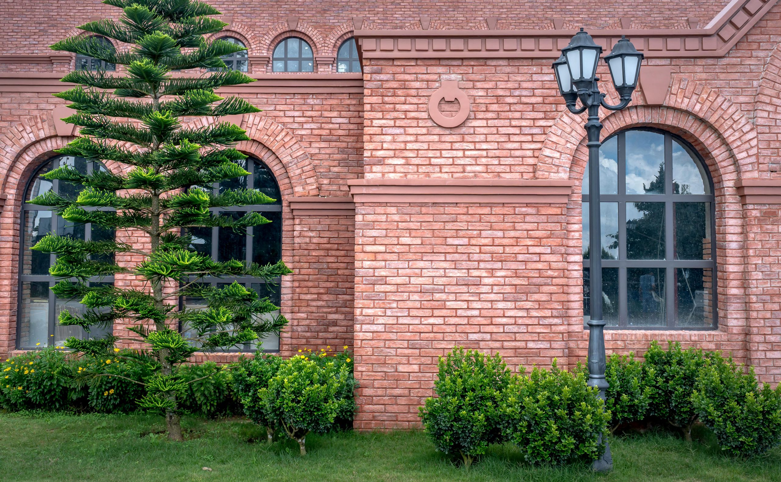 Red brick building exterior with tree and vintage lamp post.