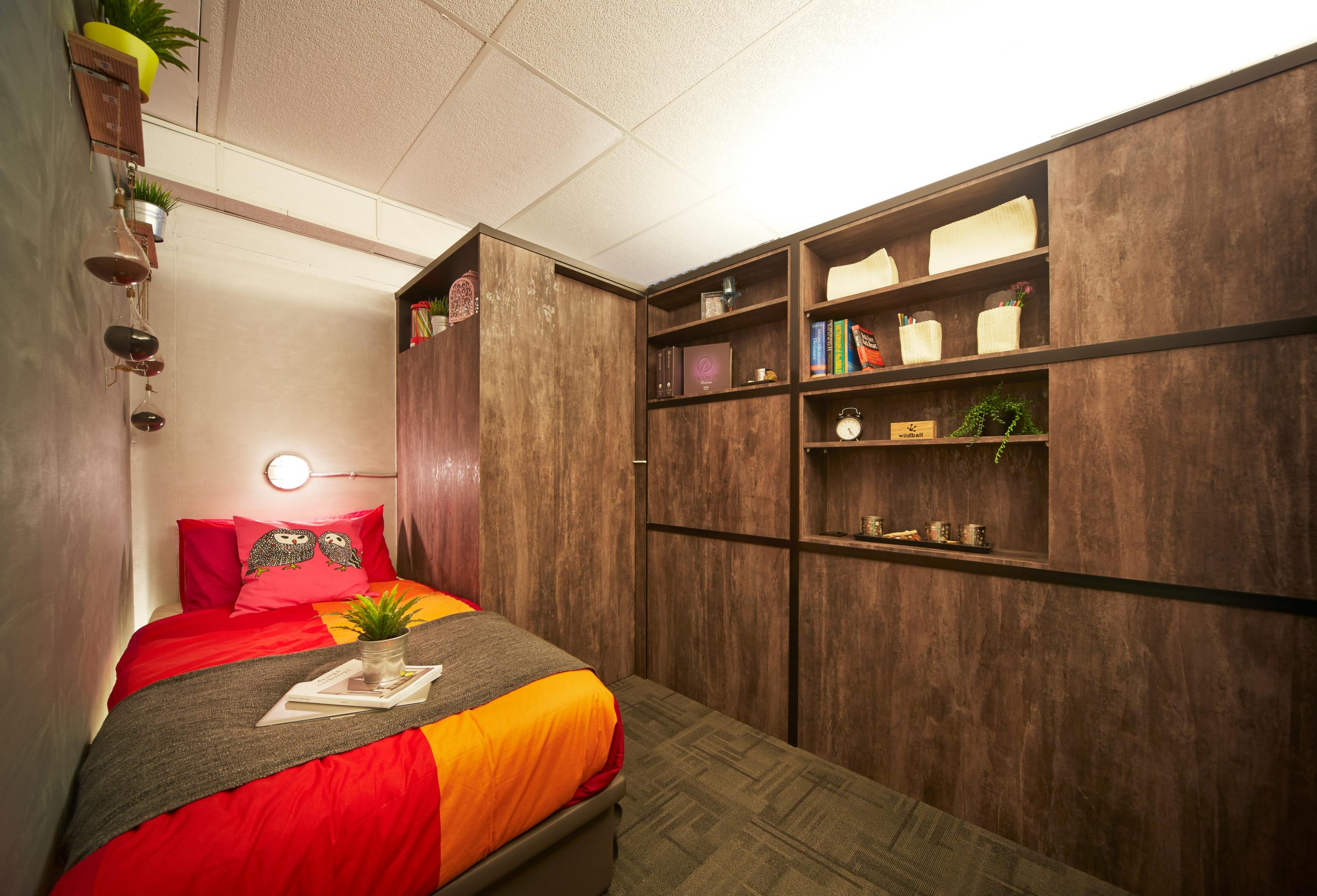 Simple bedroom interior design with colorful bed and wooden cabinet along wall in house