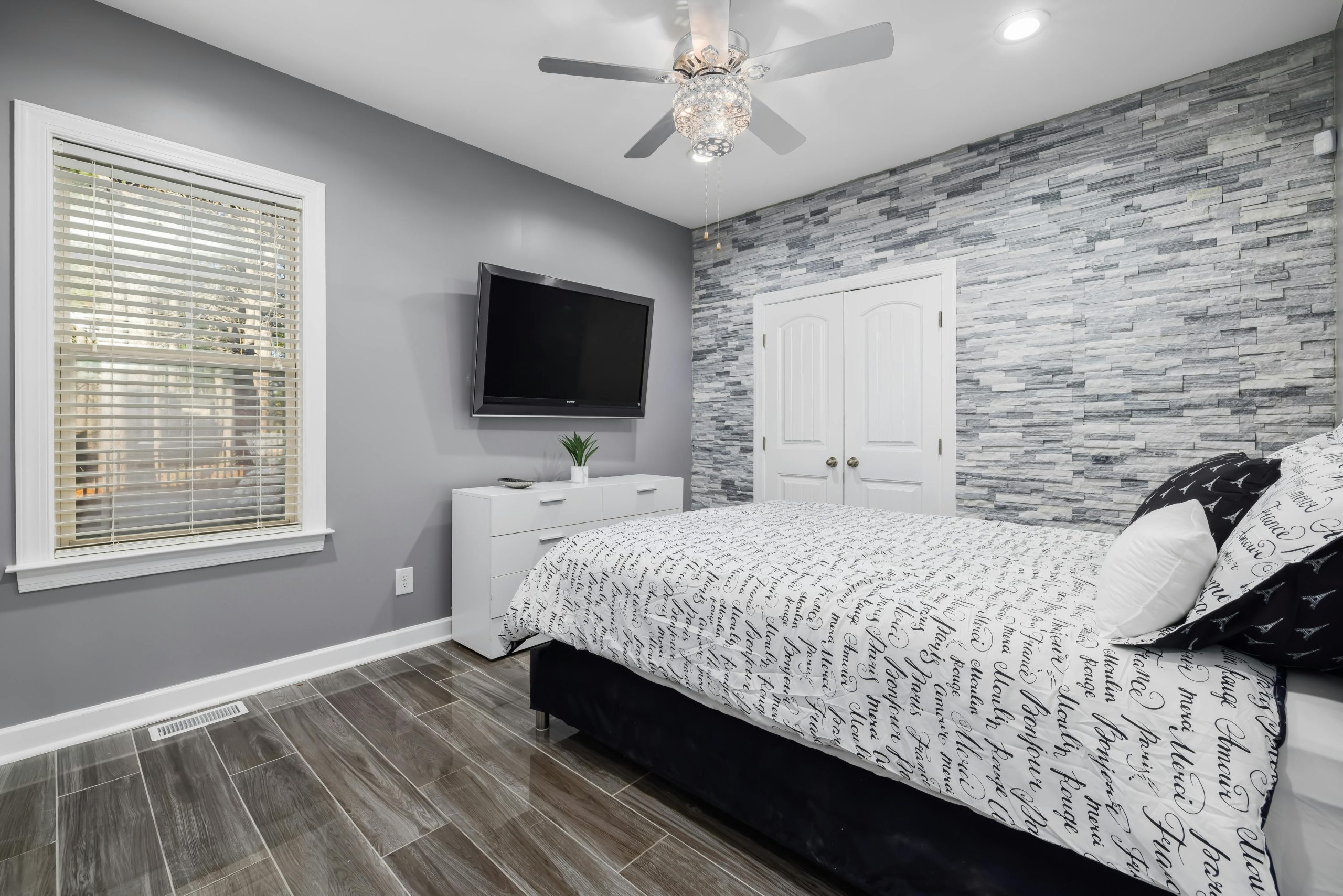 Sleek and cozy bedroom featuring modern design with stone accent wall and minimalist decor.