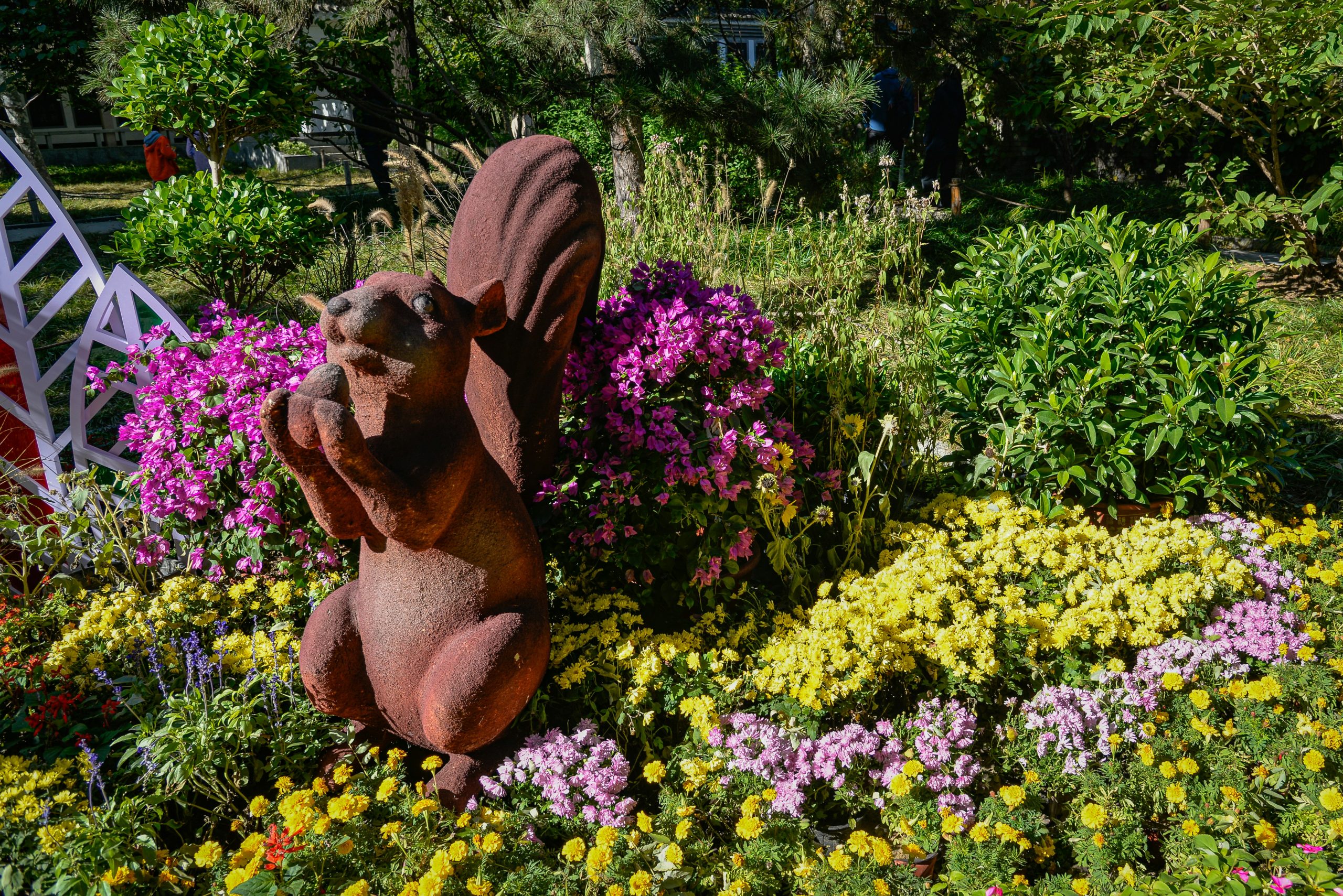 Squirrel statue in a garden with colorful flowers