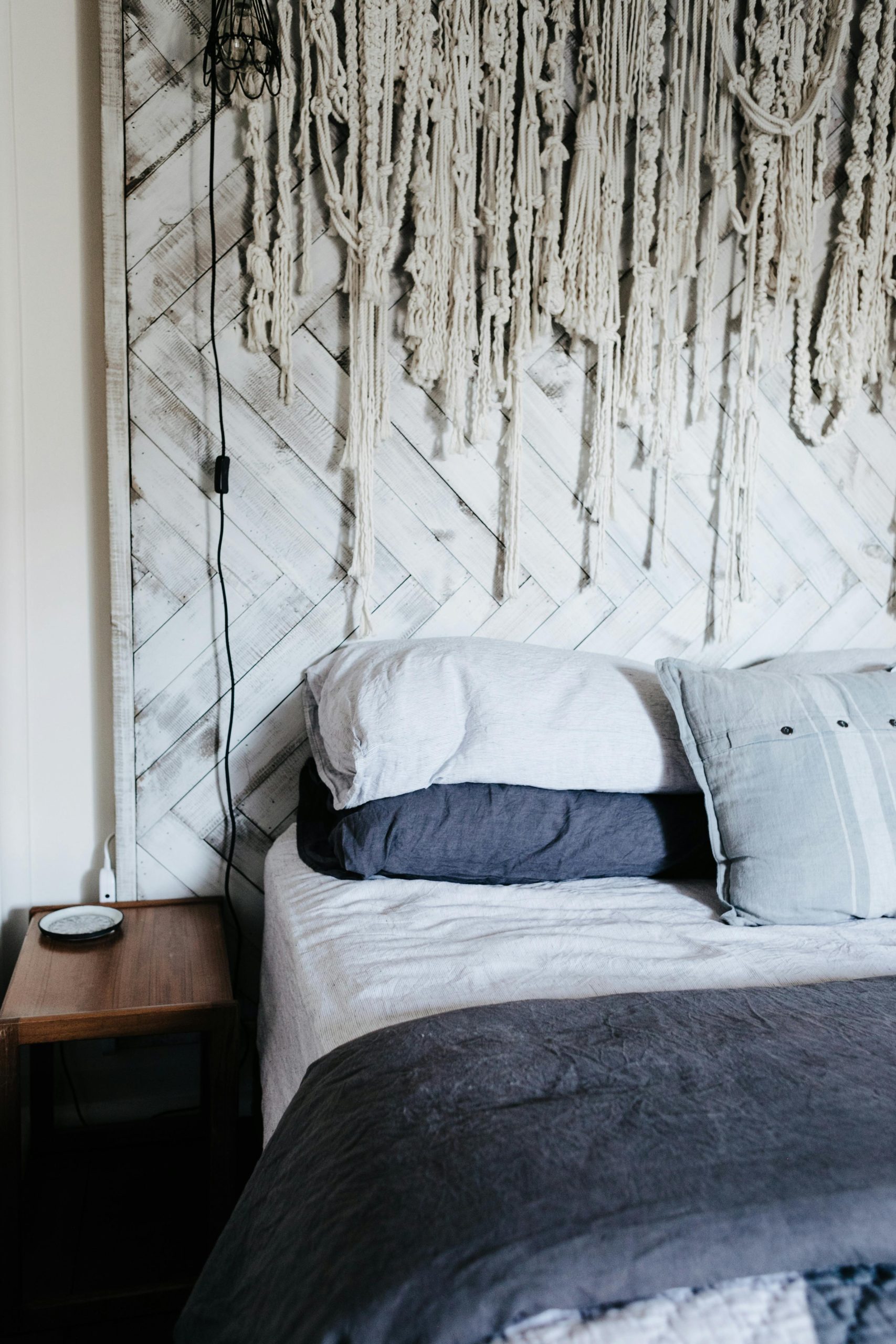 Stylish bedroom with macramé decor and layered pillows for a cozy feel.