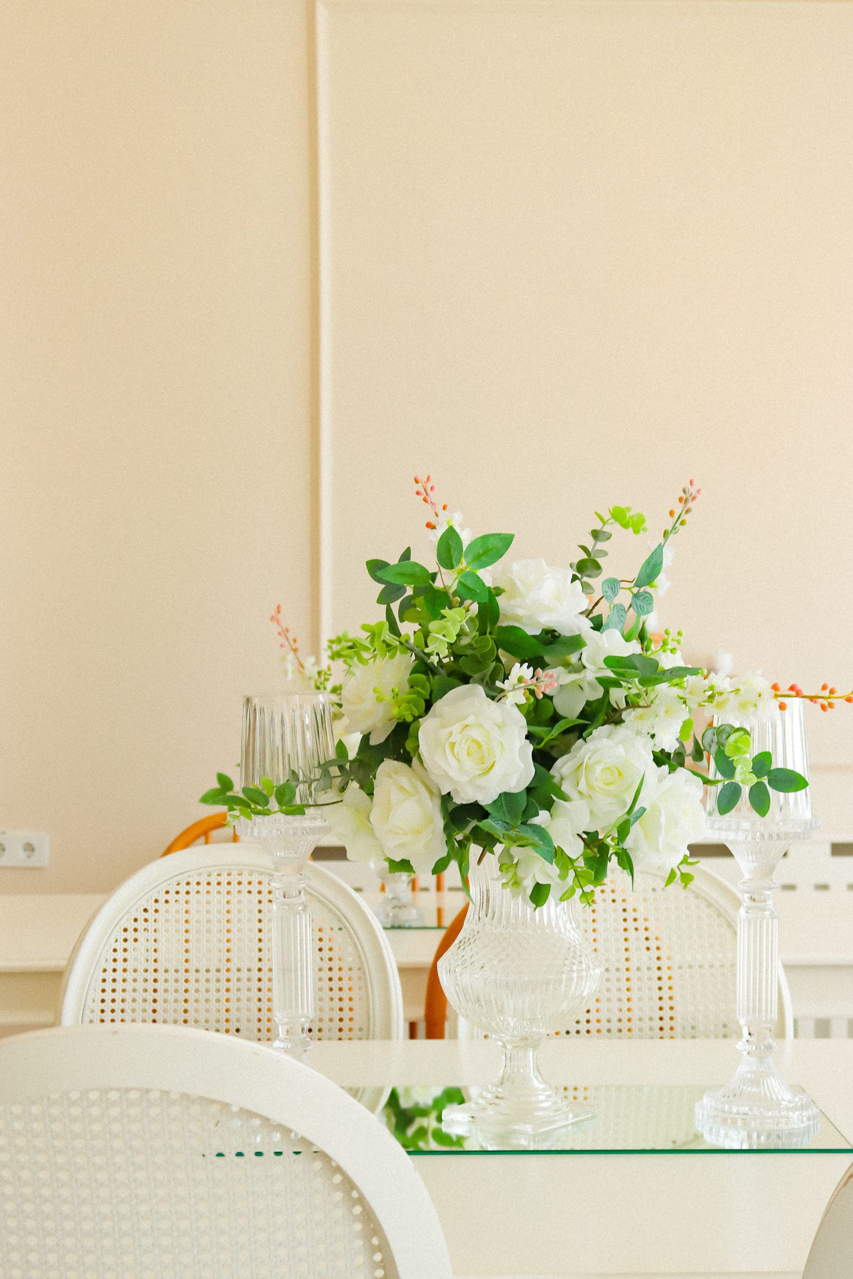 A beautiful vase of white roses decorates an elegant dining setting.