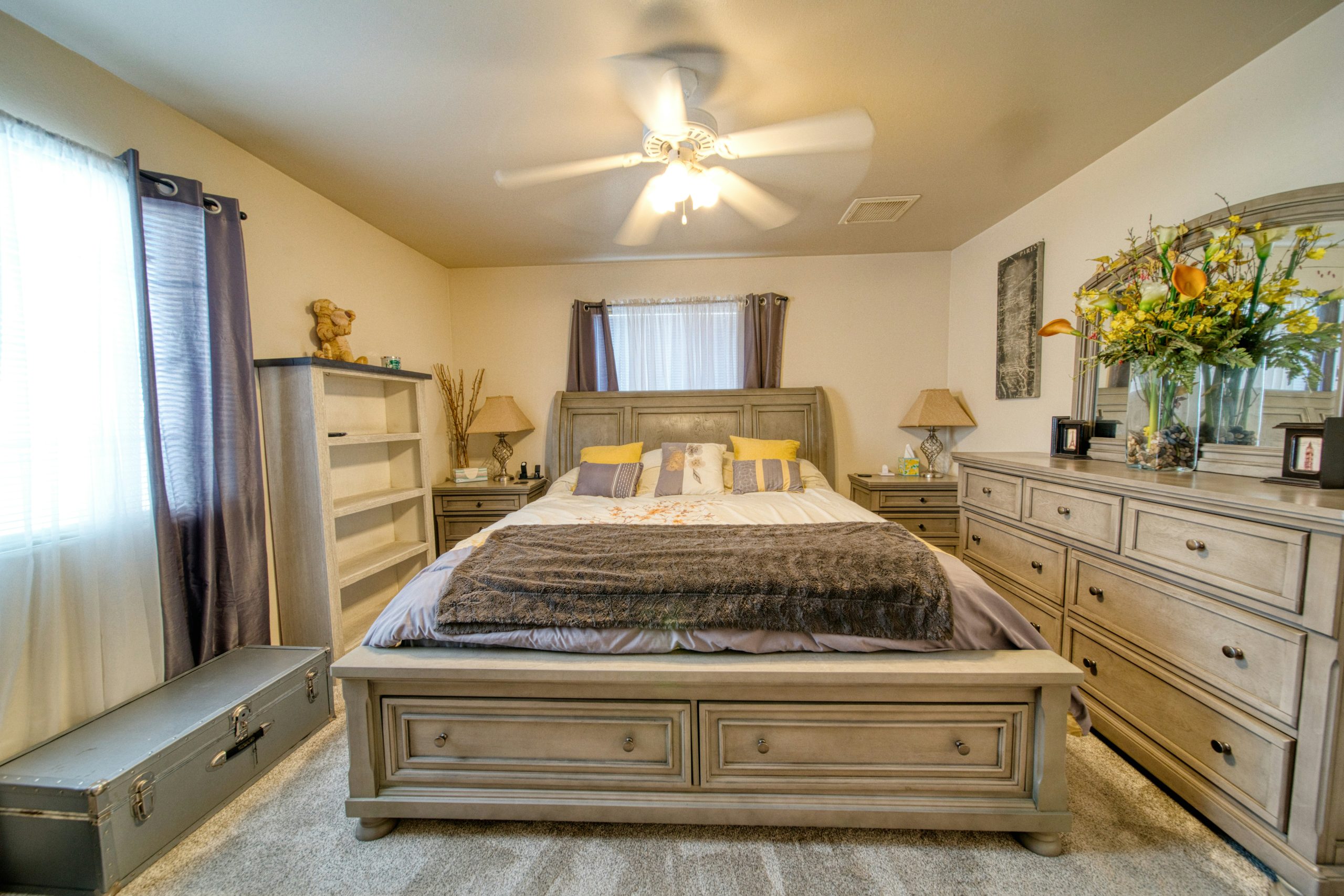 A bedroom with a bed, dressers and a mirror