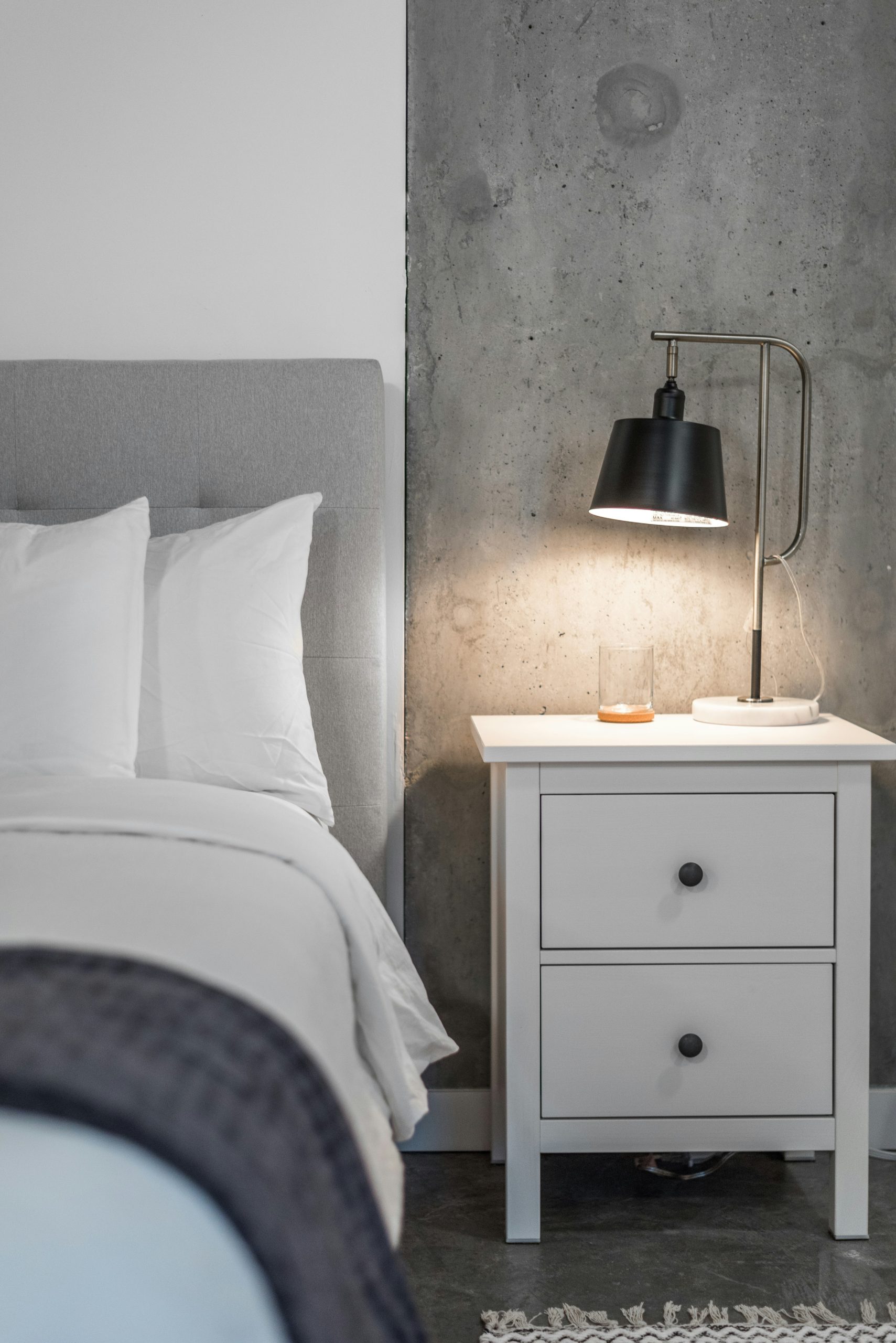 a bedroom with a bed, nightstand, and lamp