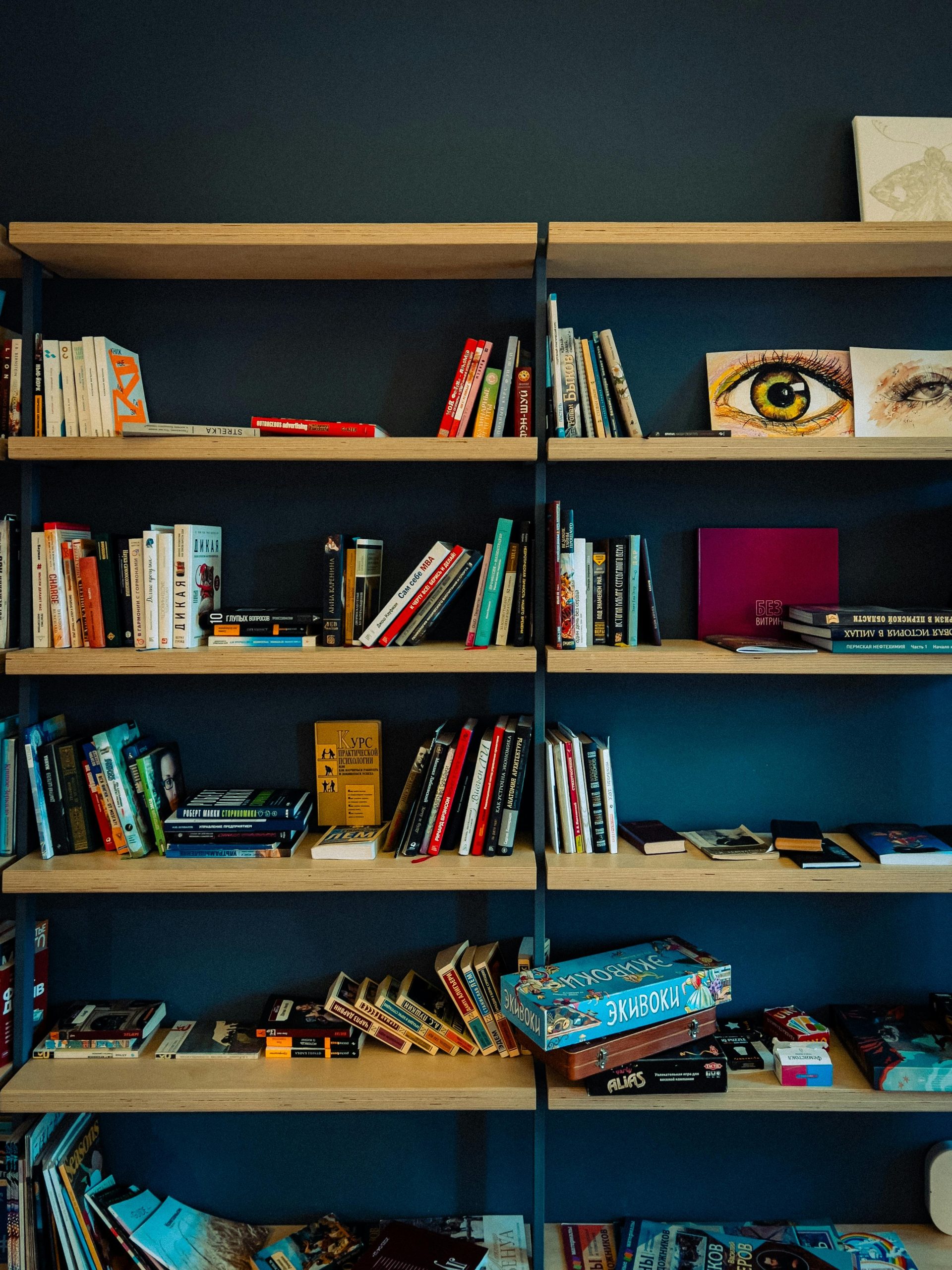A bookshelf filled with various books and creative items in a cozy setting.