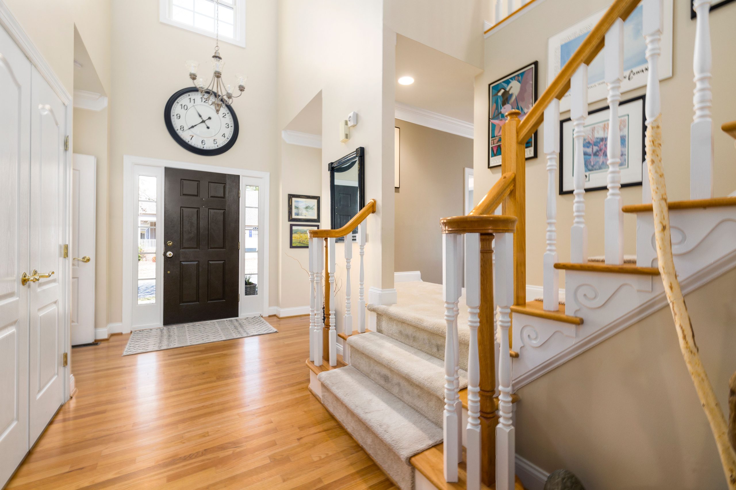 A bright and spacious modern entrance hall featuring a large clock and elegant staircase.