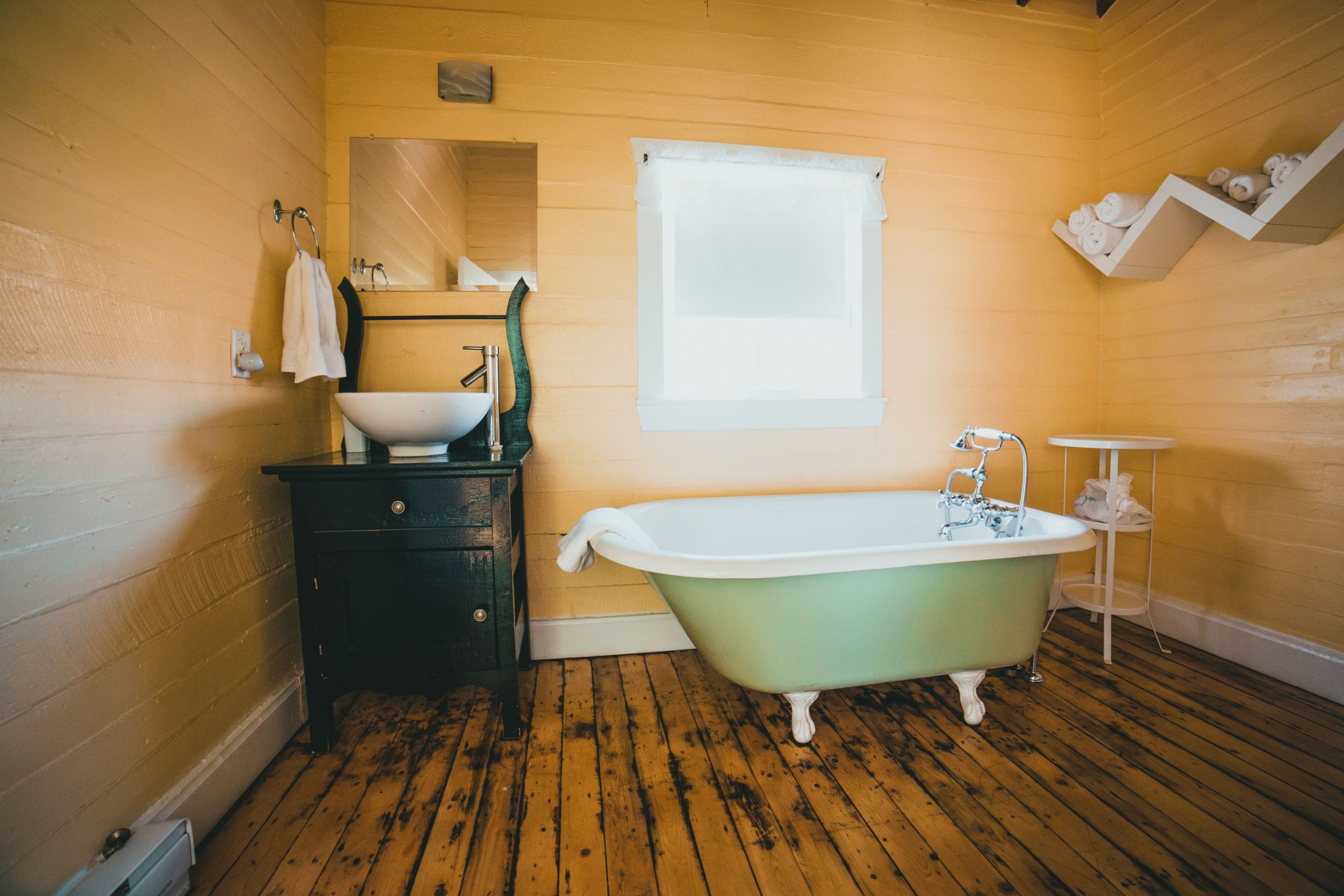 A charming rustic bathroom interior featuring a vintage clawfoot bathtub and wooden flooring.