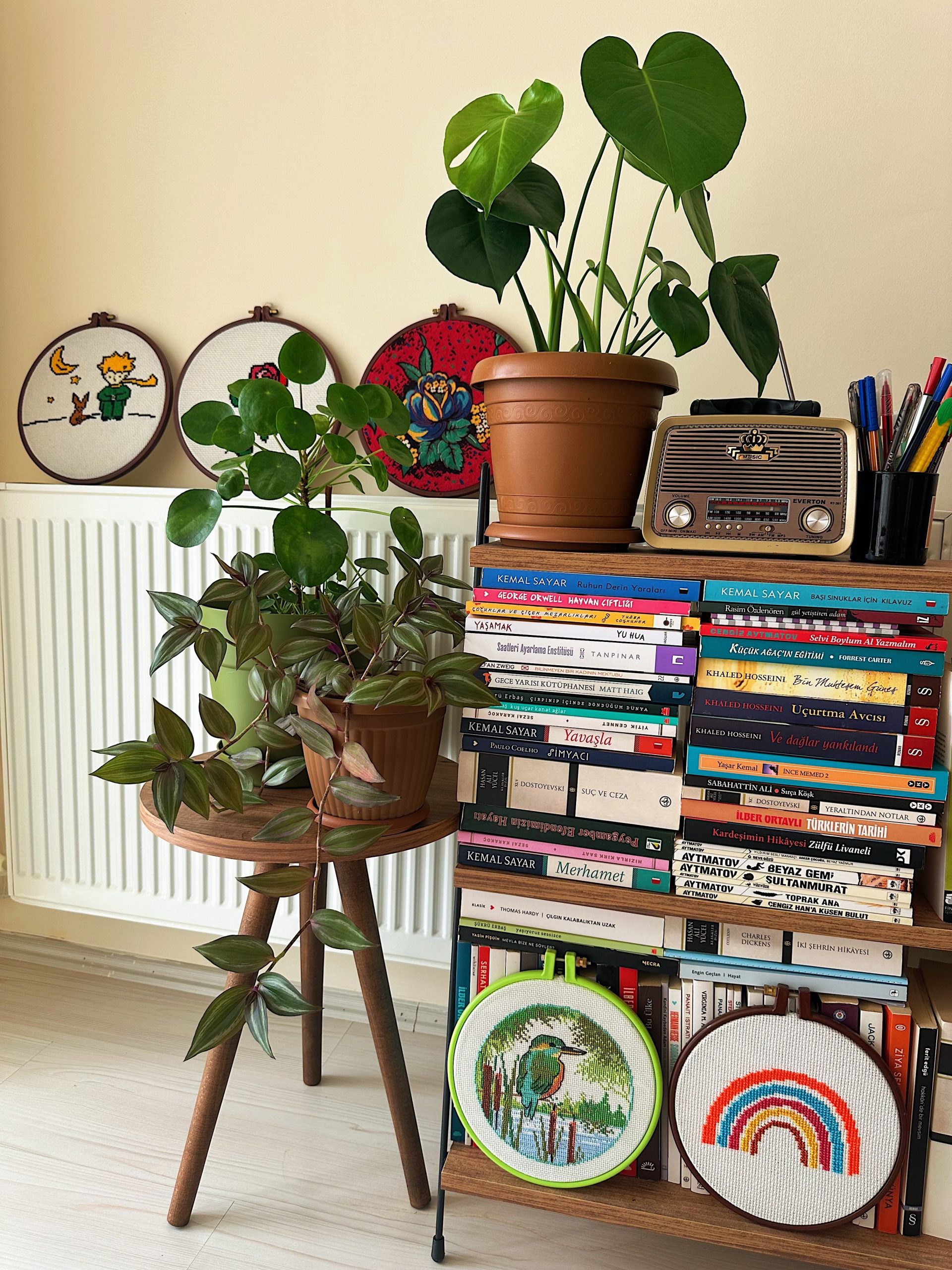 A cozy living space featuring lush plants, a bookshelf with diverse books, and vintage decor.