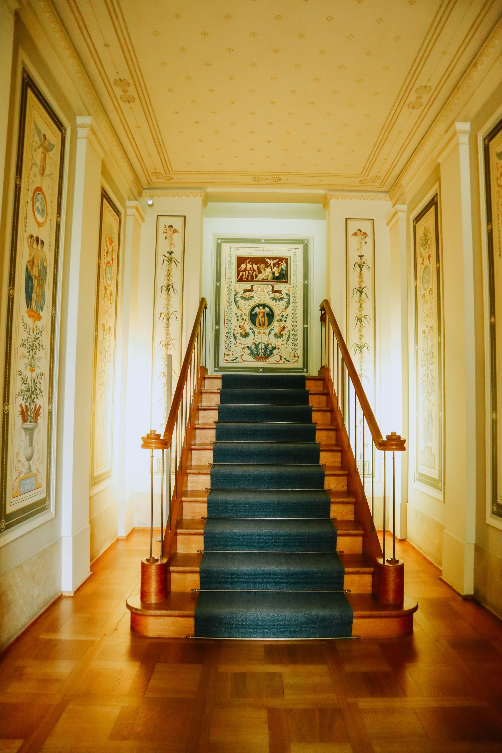 A grand staircase with vintage decor and elegant artwork in a beautifully lit hallway.