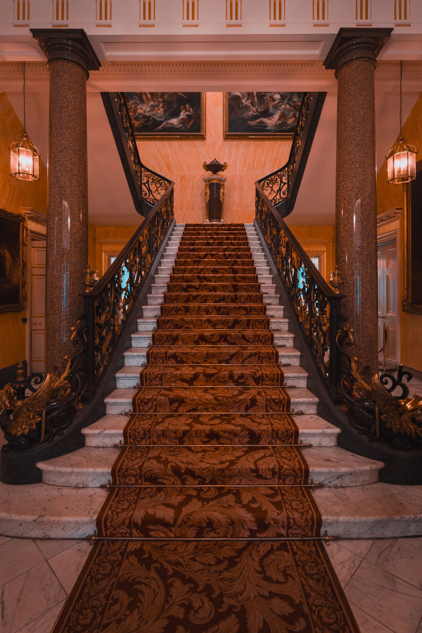 A luxurious grand staircase with ornate details inside a historic London mansion.