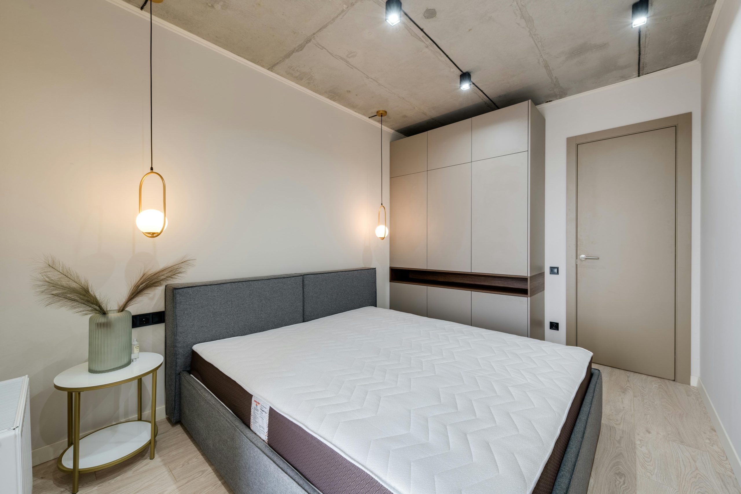 A minimalist bedroom featuring a gray bed, warm lighting, and sleek storage solutions.
