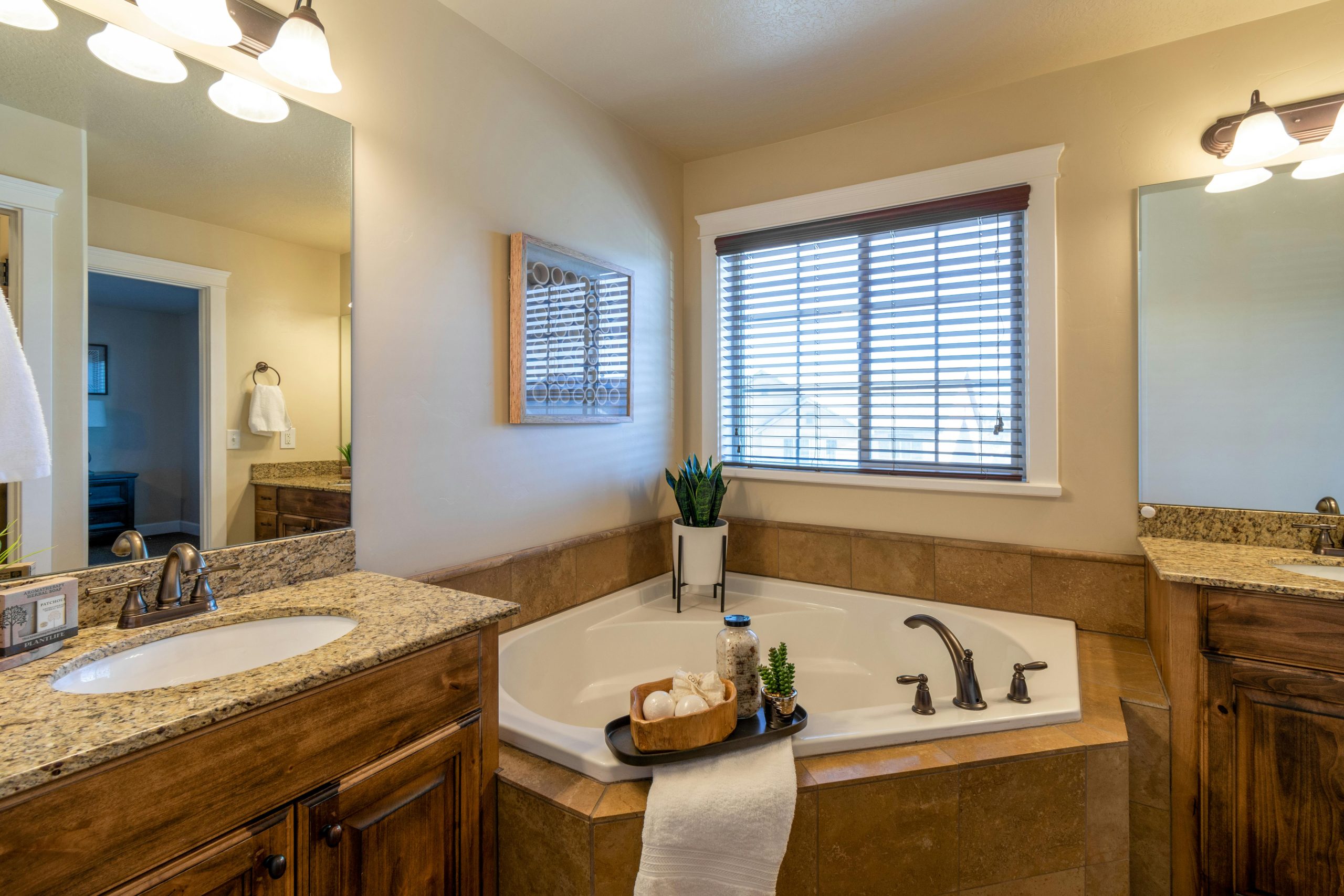 A modern bathroom interior with a bathtub, dual sinks, and warm lighting.