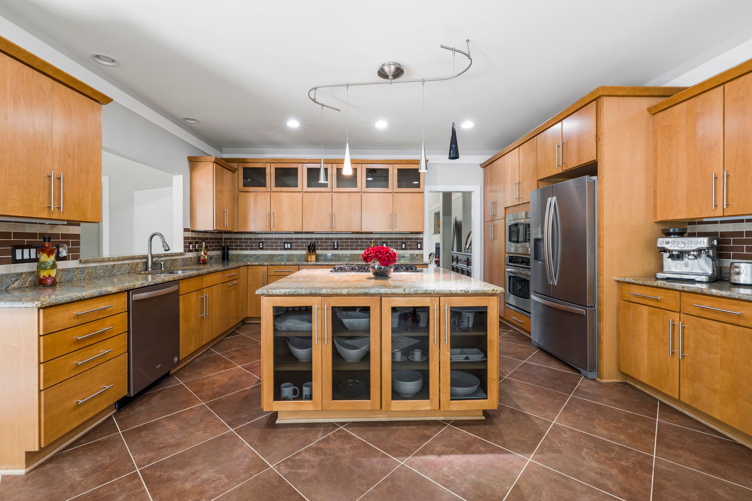 A modern kitchen featuring wooden cabinets, granite countertops, and stainless steel appliances.