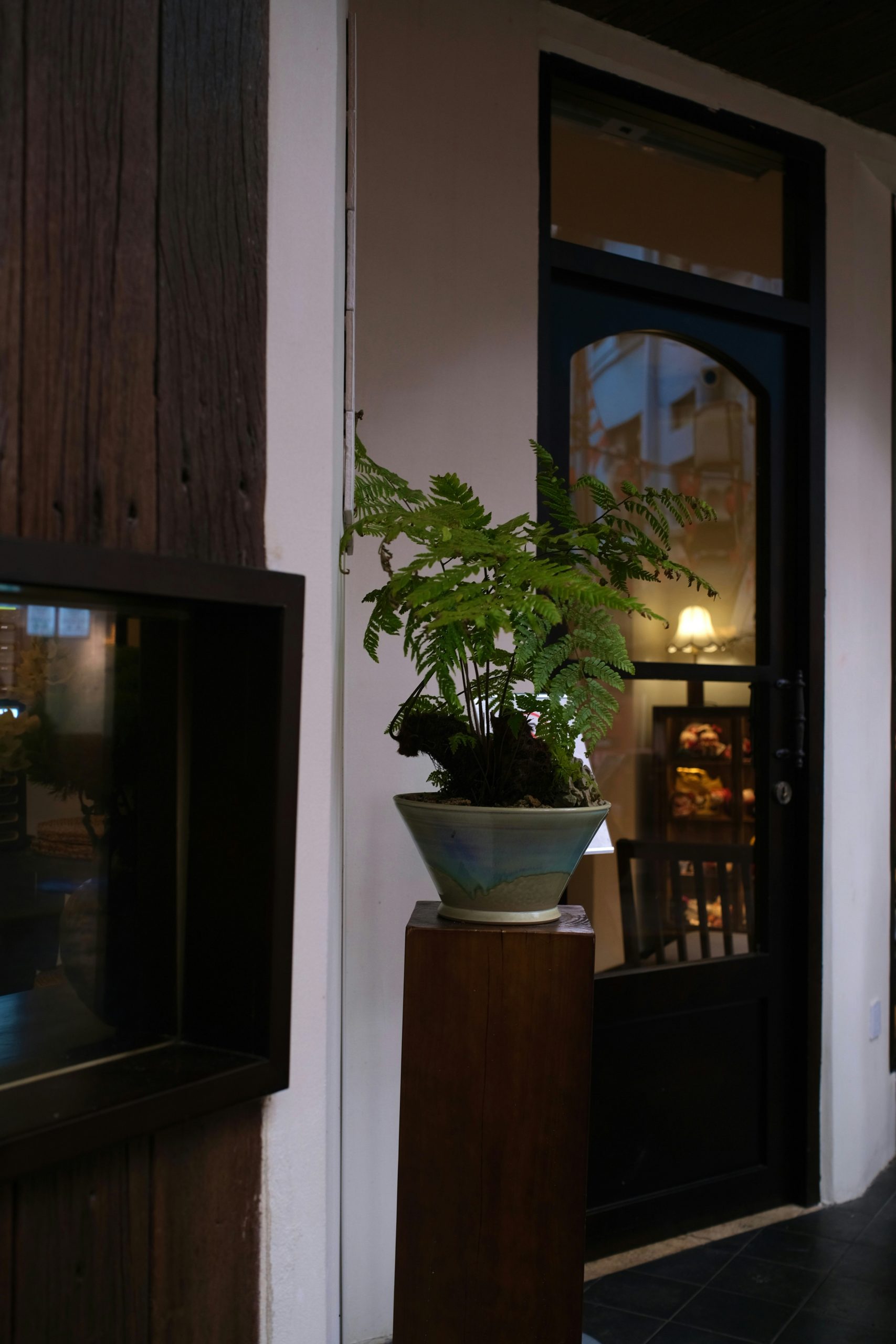 A potted fern sits on a wooden stand.