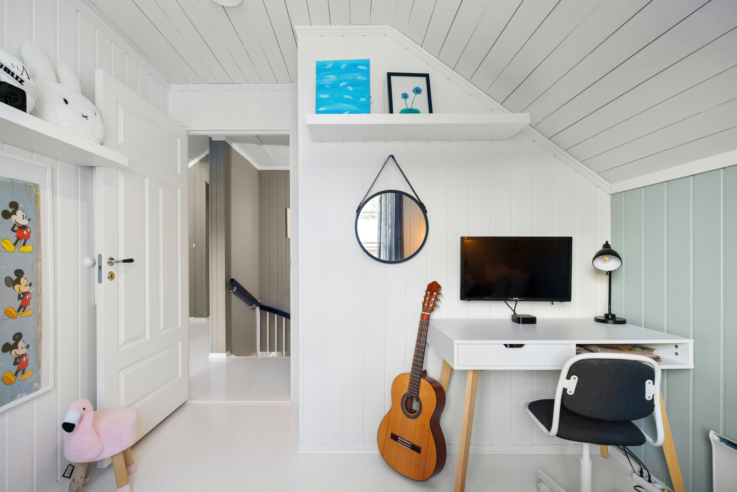 A room with a desk and a guitar