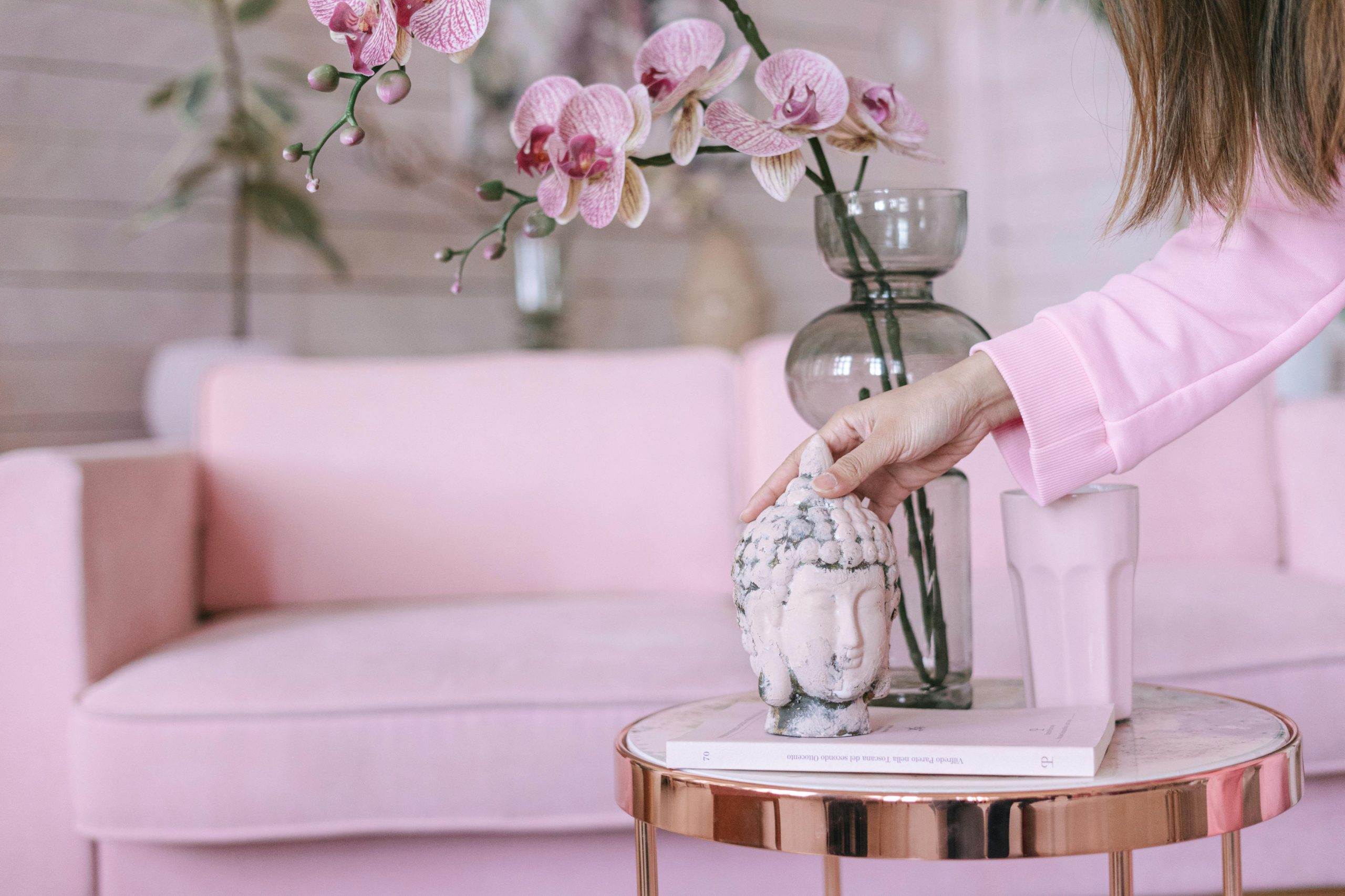 A serene living room scene with a Buddha head statue, pink orchids, and modern decor.