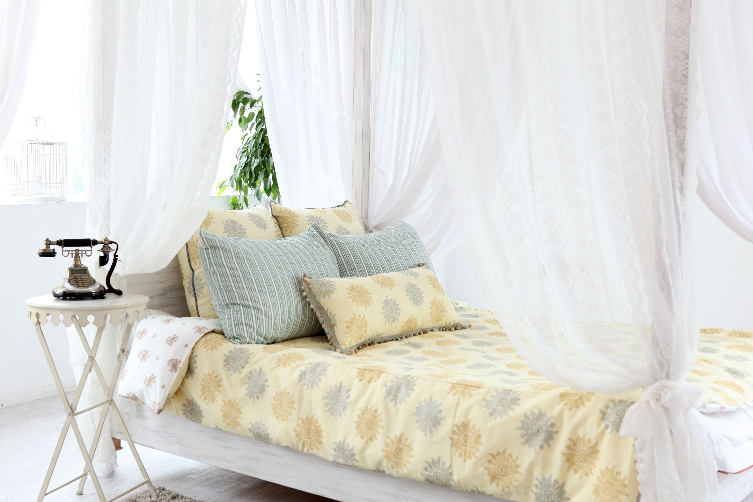 A serene vintage bedroom with plush pillows, lace curtains, and antique decor, perfect for cozy interiors.