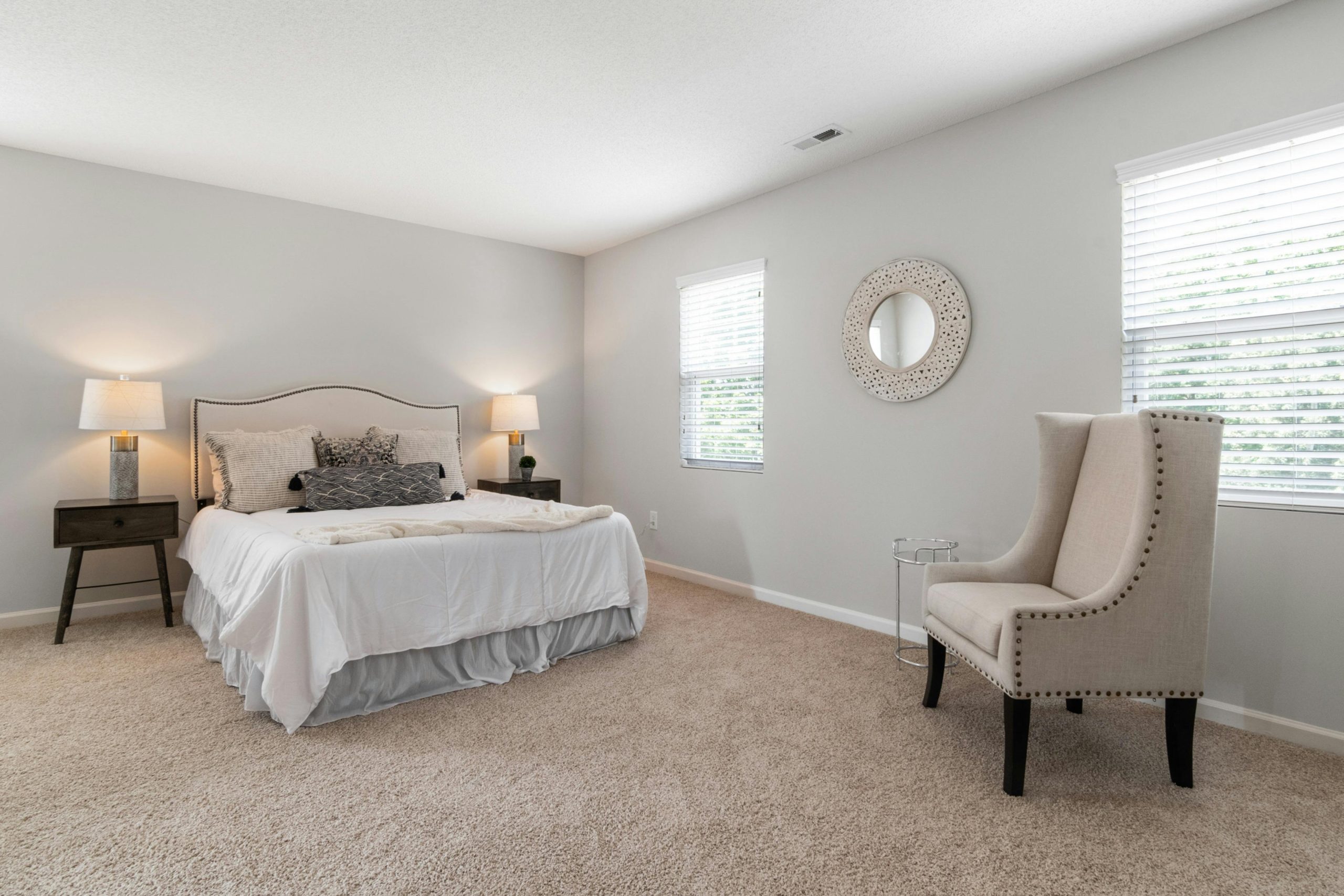 A spacious and bright modern bedroom featuring minimalistic decor and neutral tones.