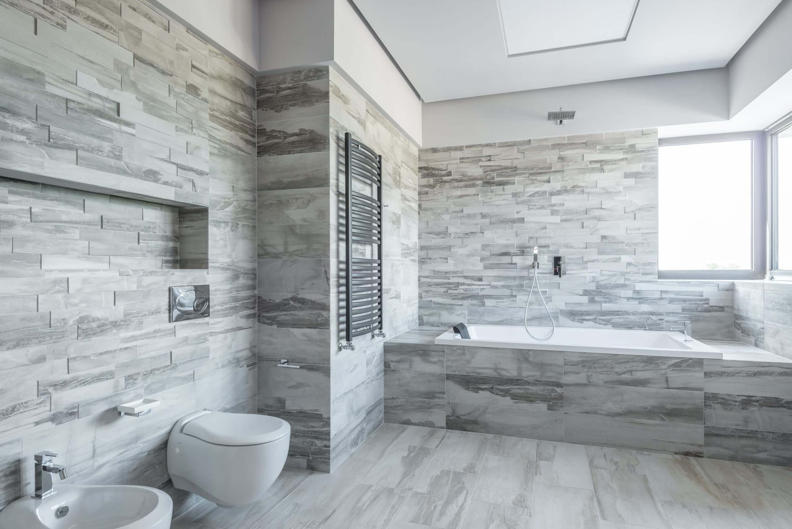A spacious and stylish bathroom featuring modern design elements like a sleek bathtub and stone tiles.