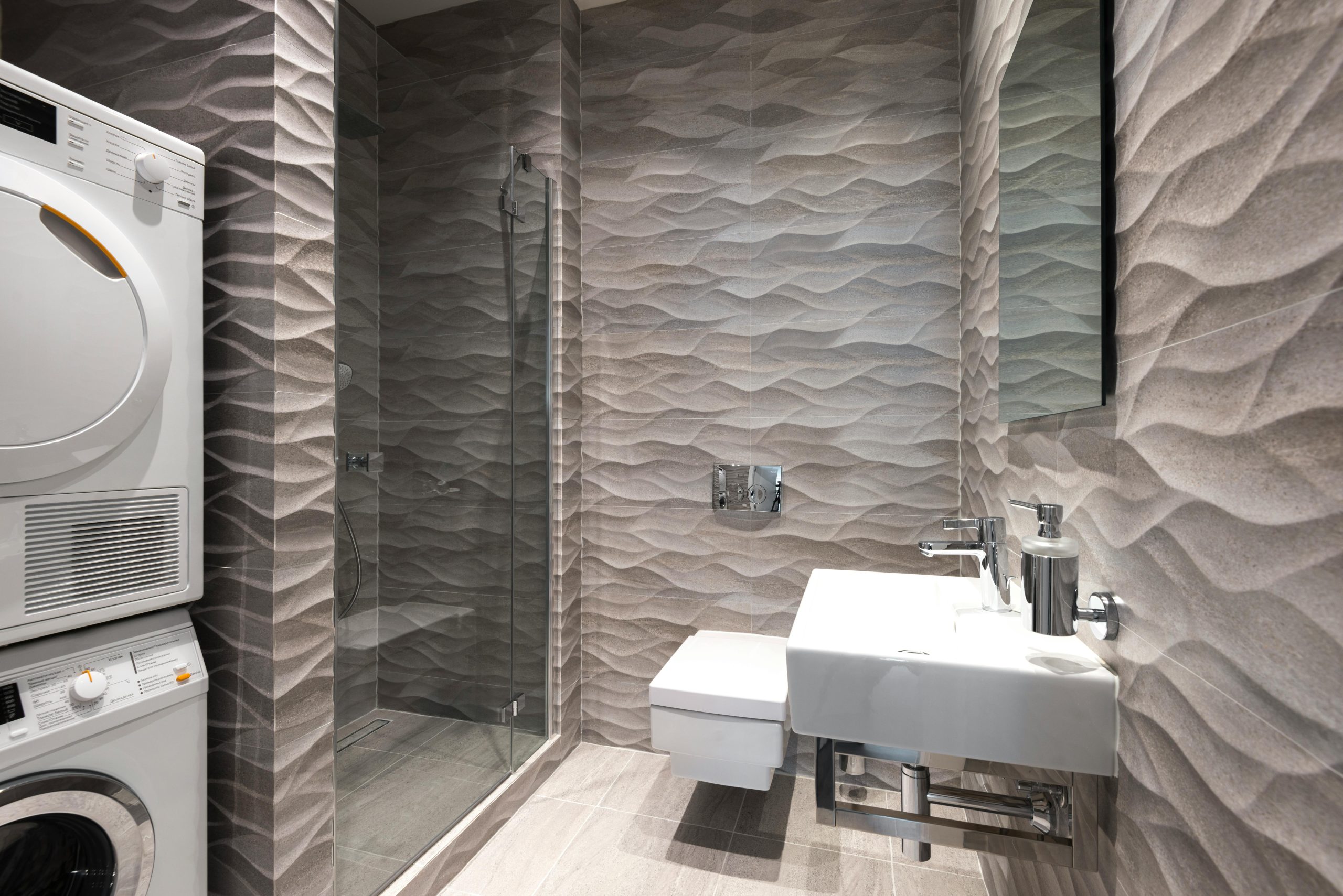 A stylish and contemporary bathroom featuring a shower, sink, and in-built washer and dryer.