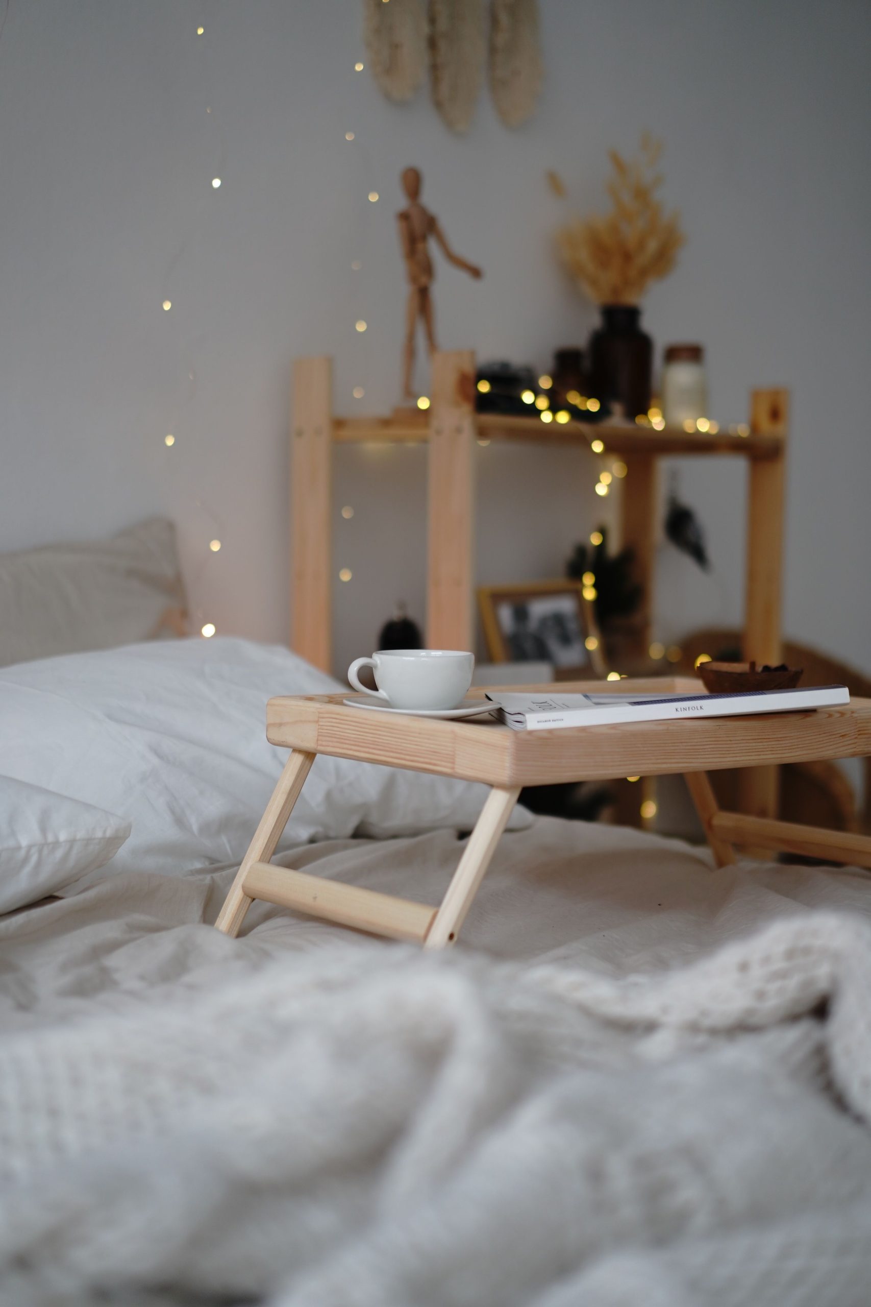 A warm and inviting boho bedroom scene with a breakfast tray, coffee, and soft lighting.