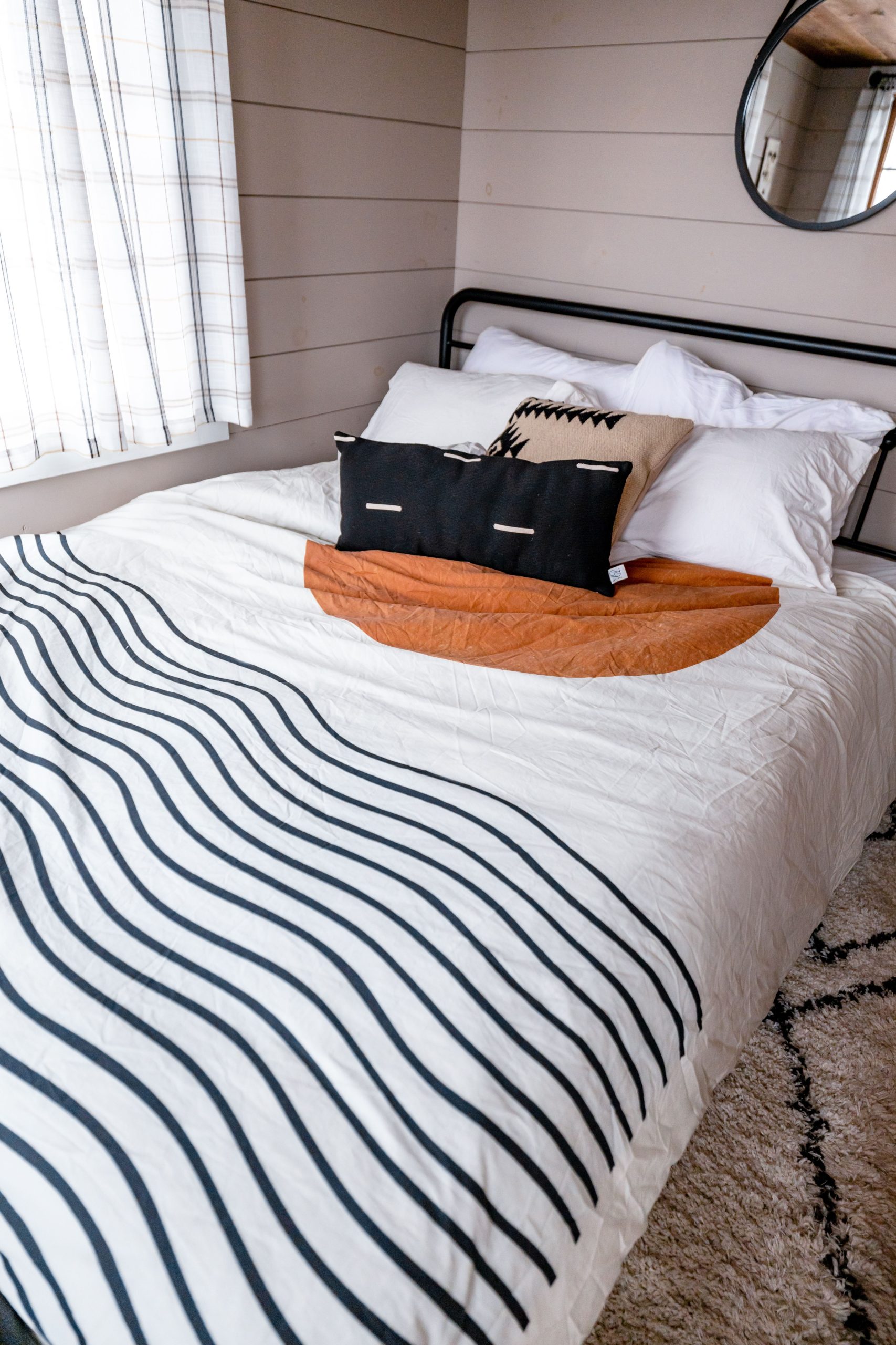 A well-decorated bed in a modern bedroom featuring stylish pillows and linens.